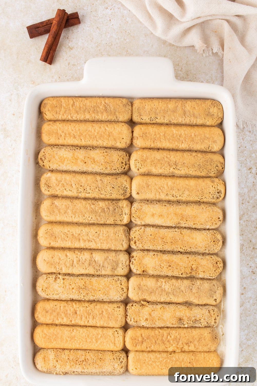dipped ladyfingers in a casserole dish on the table 