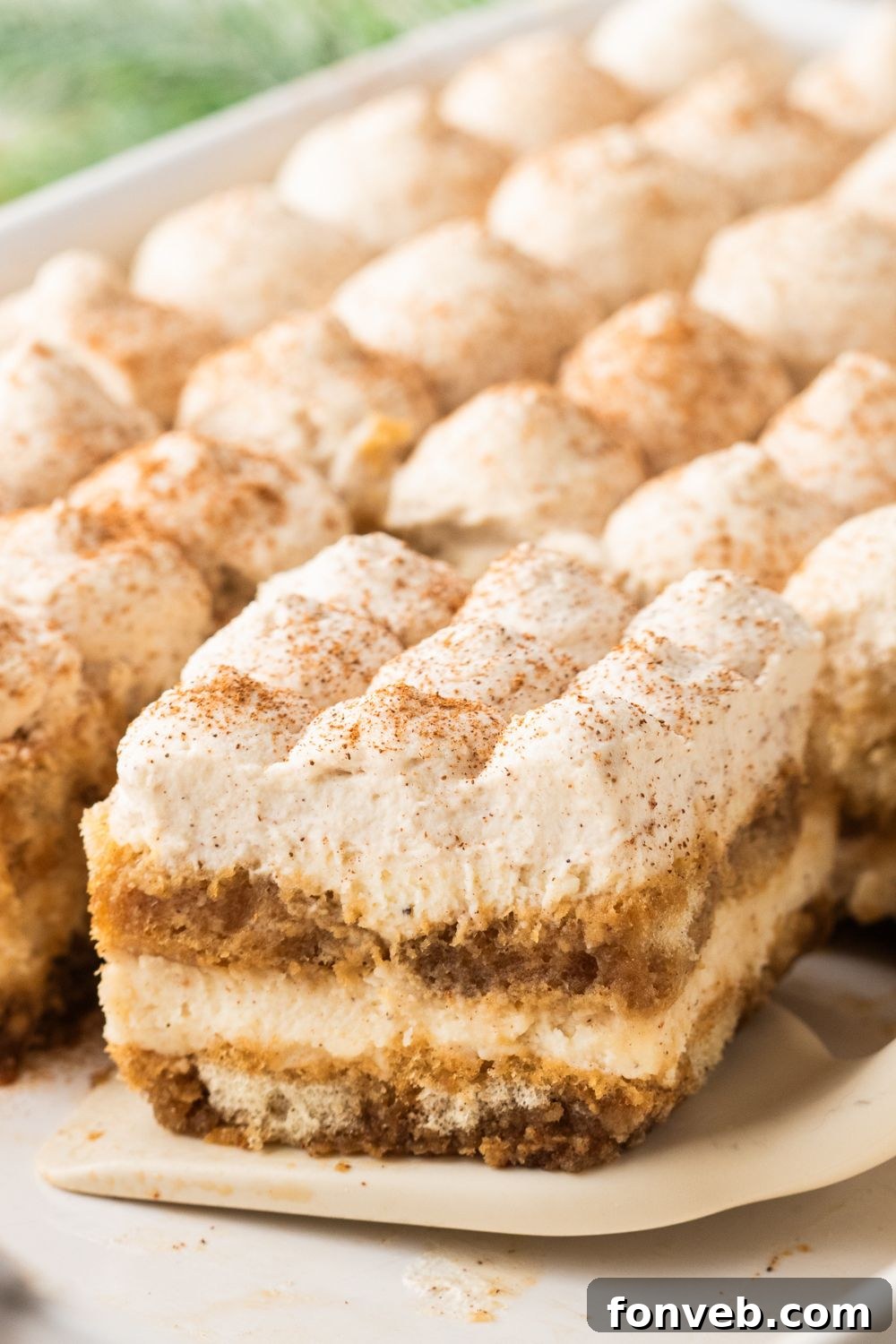 a slice of eggnog tiramisu sliced and lifting out of the casserole pan