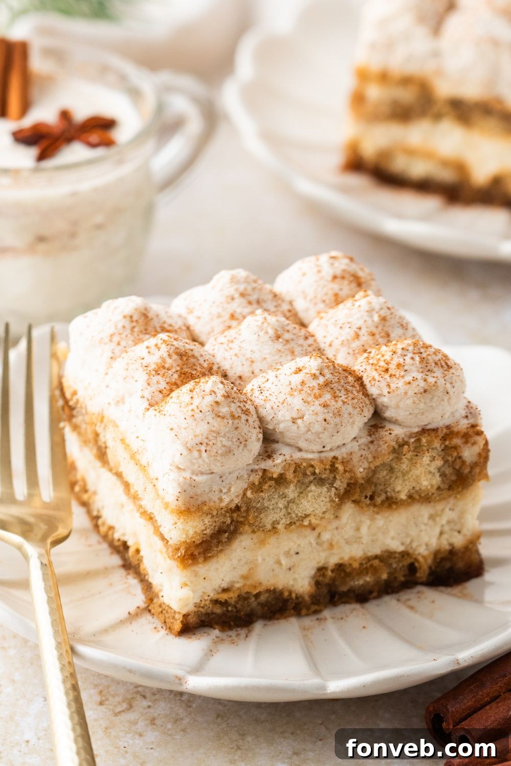 Eggnog Tiramisu sliced on white plates with a glass of eggnog behind the plate 