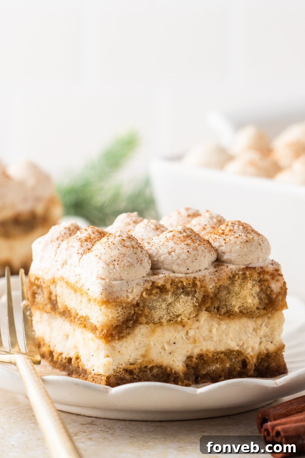 slice of eggnog dessert sliced and placed on plate with more plates in the background 