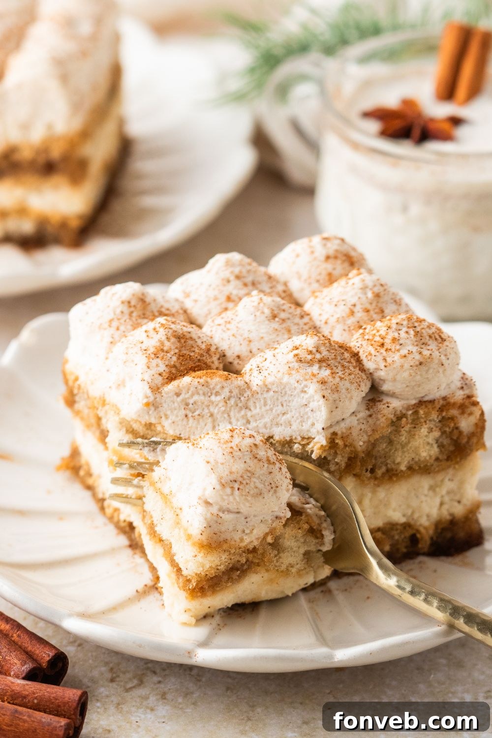 fork cutting into a slice of Eggnog Tiramisu on a white plate on table 