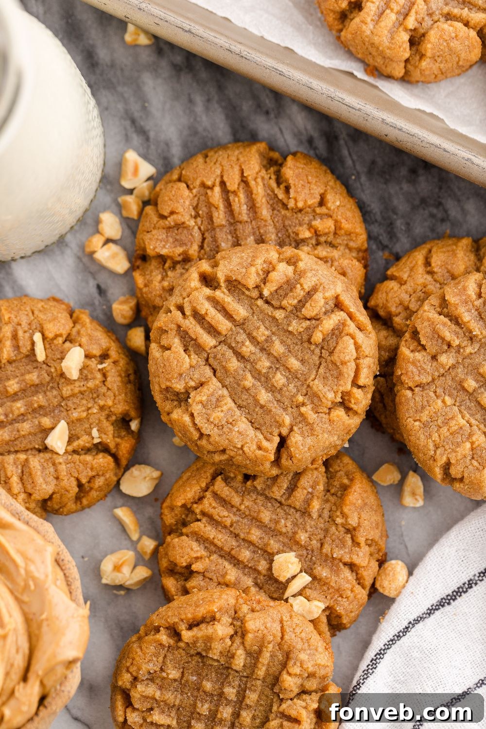 Easy 4-Ingredient Flourless Peanut Butter Cookies 13 4 Ingredient Peanut Butter Cookies spread around the table with a tall glass of milk in a jar with a try with more cookies to side