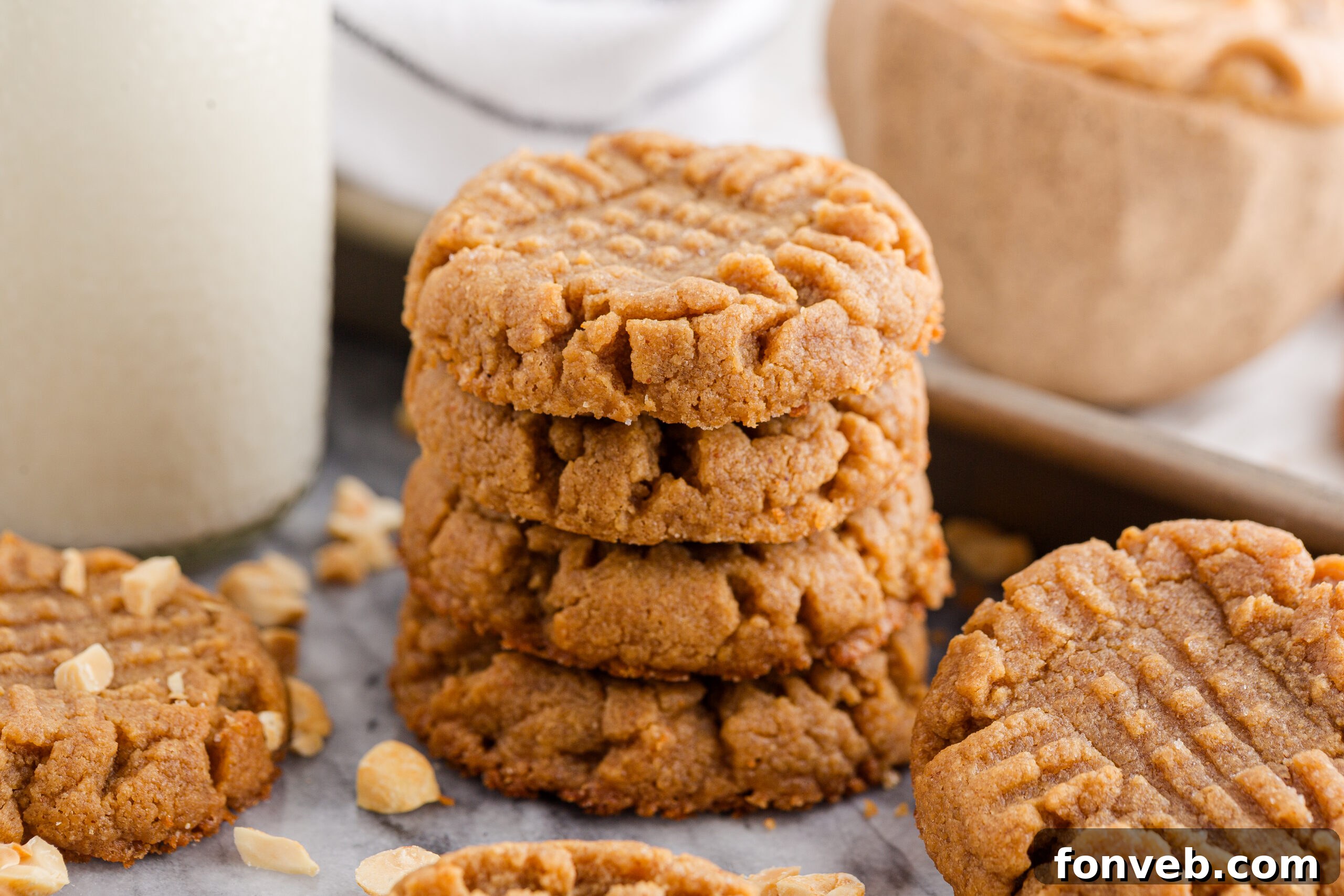 Easy 4-Ingredient Flourless Peanut Butter Cookies 15 4 Ingredient Peanut Butter Cookies spread around table with a tray full of cookies behind and a tall jar of milk