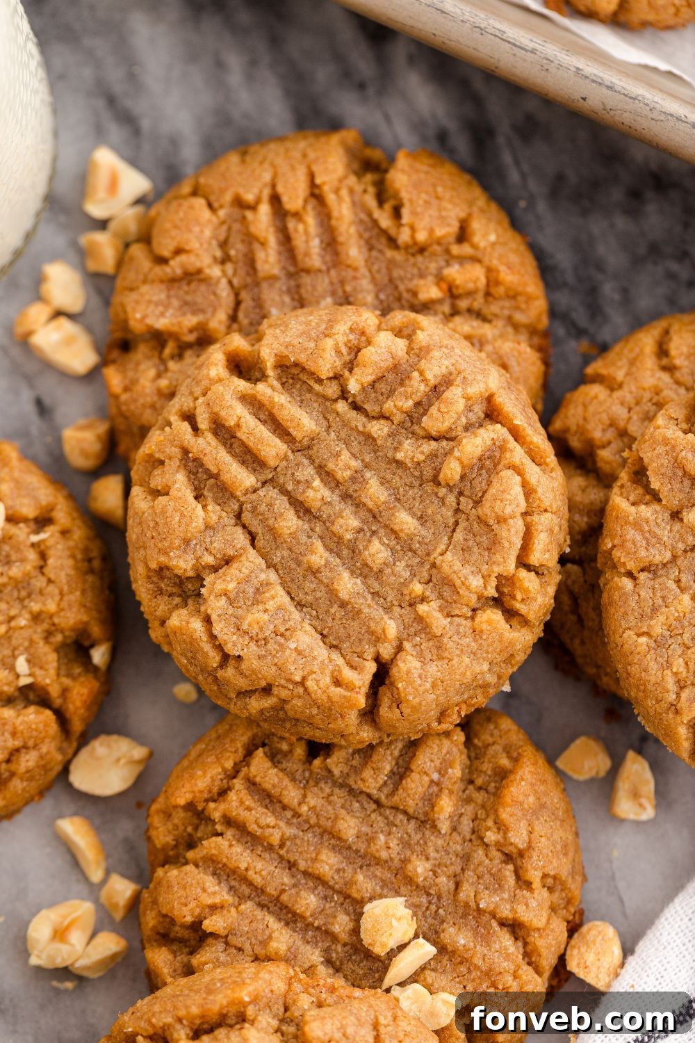 Easy 4-Ingredient Flourless Peanut Butter Cookies 19 marble counter with more peanut butter cookies stacked on the table with peanuts scattered around the table