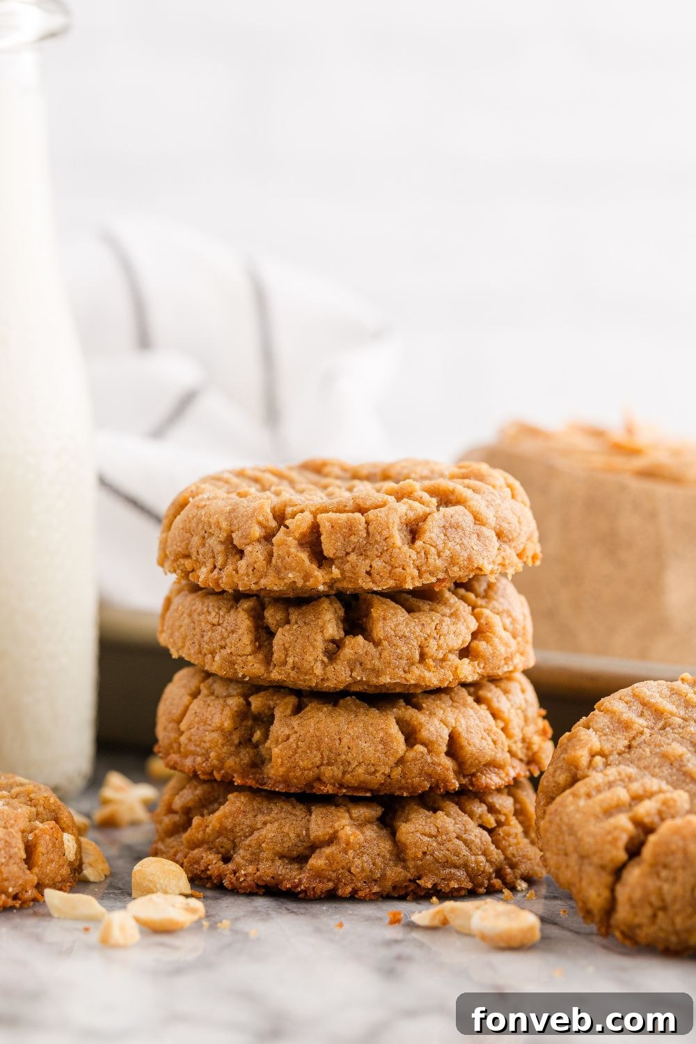 Easy 4-Ingredient Flourless Peanut Butter Cookies 22 stack of peanut butter cookies with nuts all around it and glass of milk to the side of the cookies