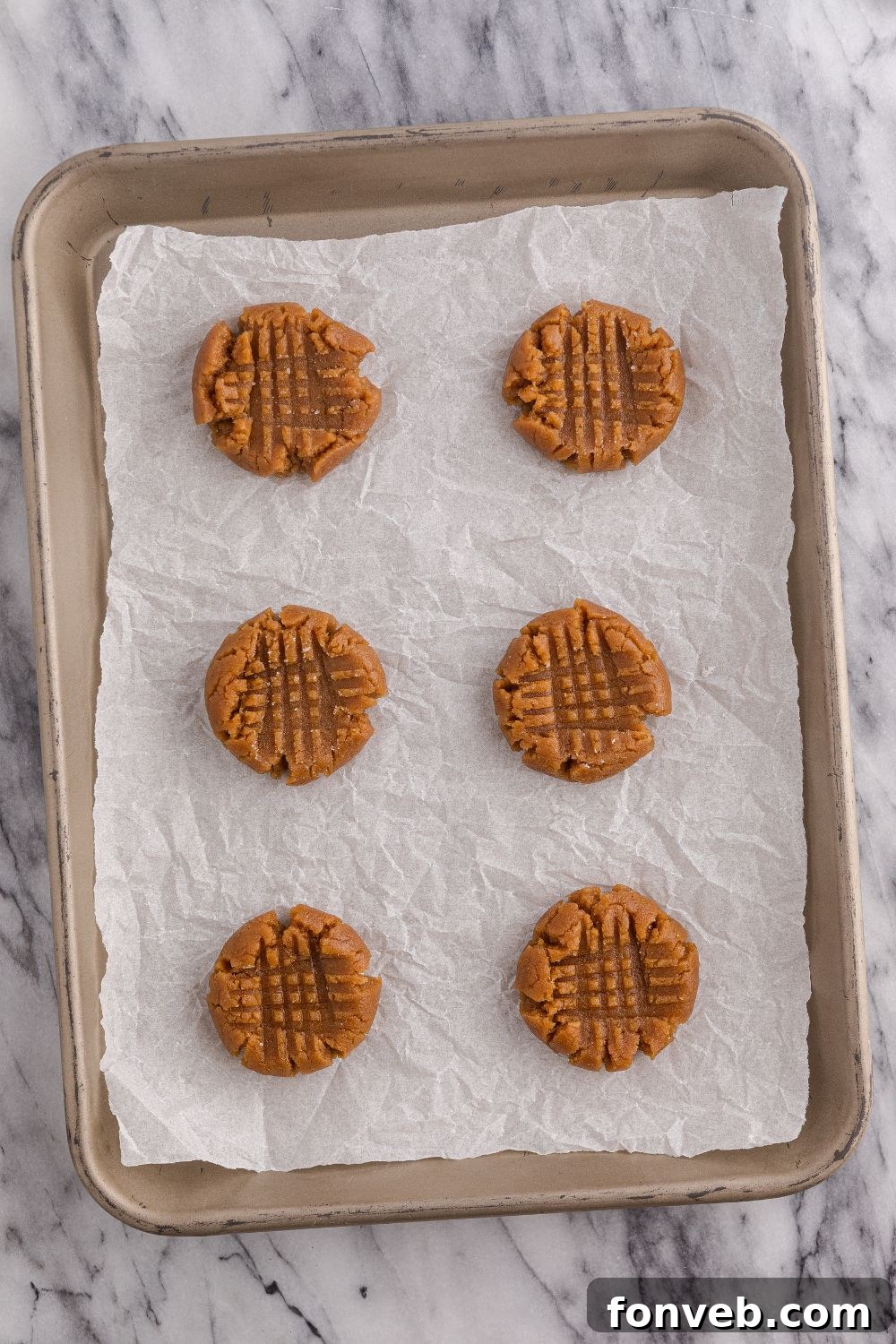 Easy 4-Ingredient Flourless Peanut Butter Cookies 8 raw peanut butter cookies on the cookie sheet tray
