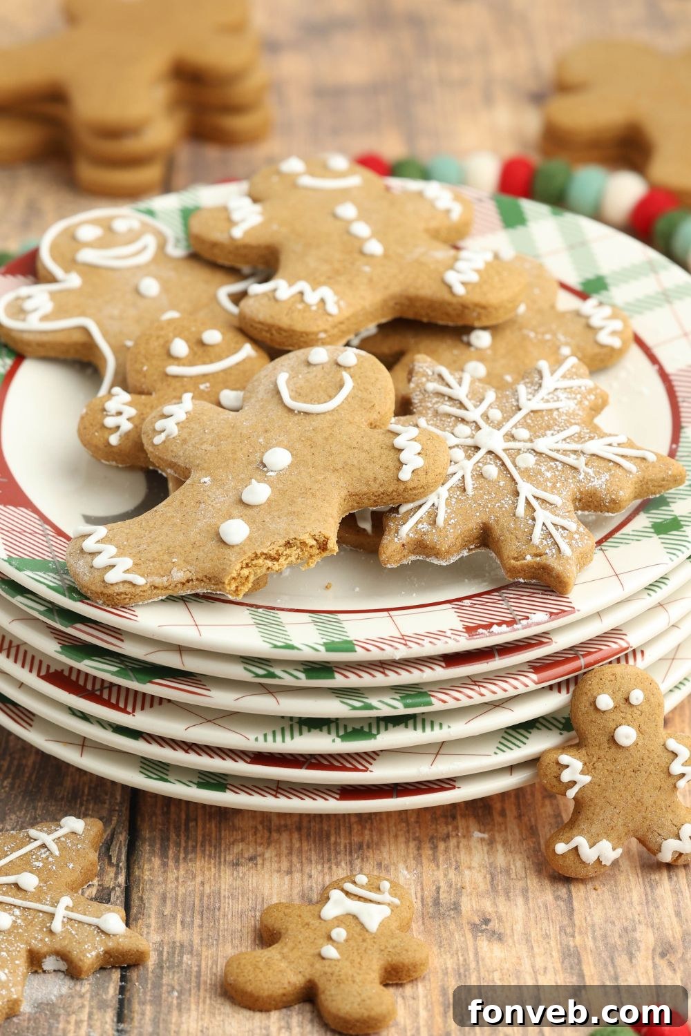 Dazzling Christmas Gingerbread Adorned With Royal Icing 12 stack of plates and on top is gingerbread cookies with one with a bite taken out of it