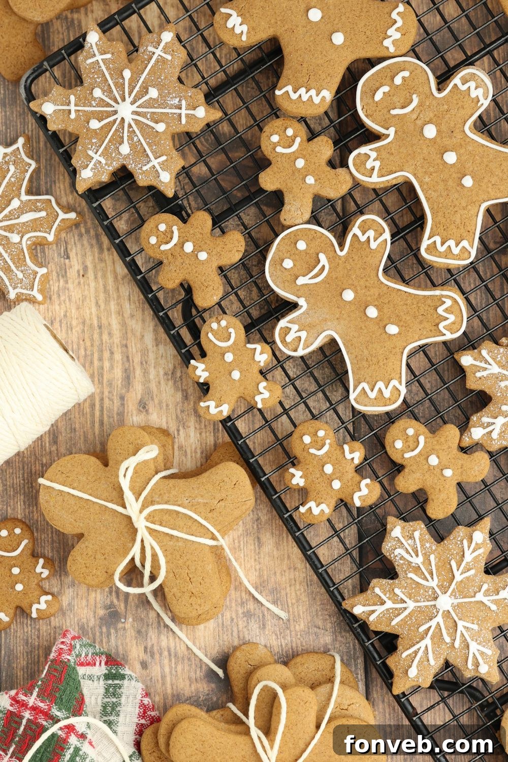 Dazzling Christmas Gingerbread Adorned With Royal Icing 14 cooling rack full of different shapes of Christmas gingerbread cookies and on table with string and more for Christmas