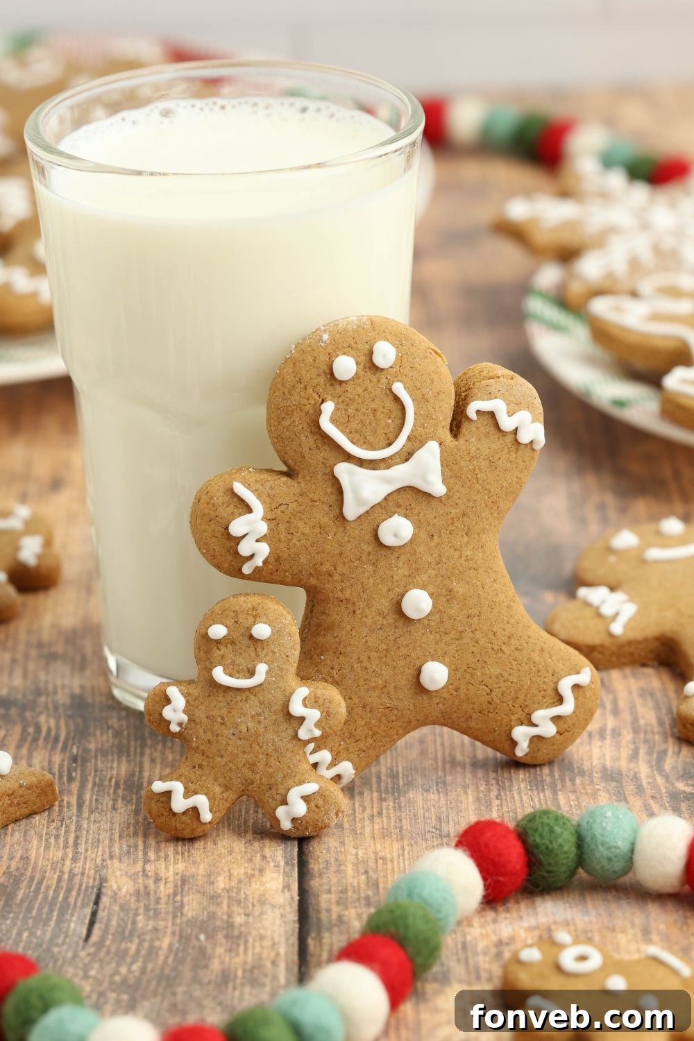 Dazzling Christmas Gingerbread Adorned With Royal Icing 17 tall glass of milk with two gingerbread cookies standing on side and more cookies around the table