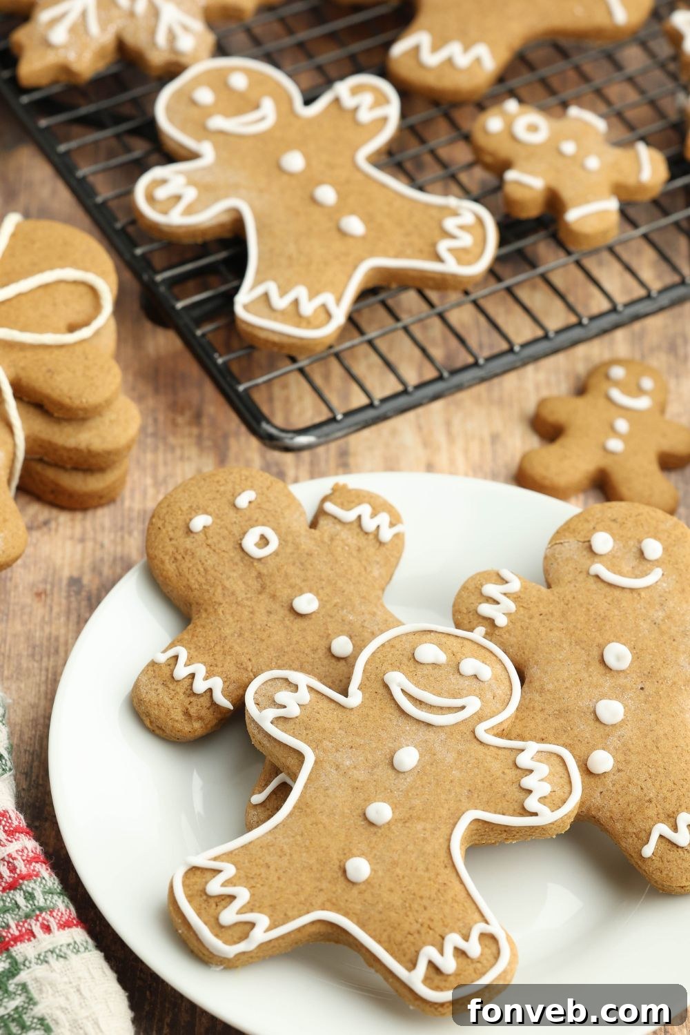 Dazzling Christmas Gingerbread Adorned With Royal Icing 3 Christmas gingerbread cookies spread around the table and a cooling rack full of more cookies around the table