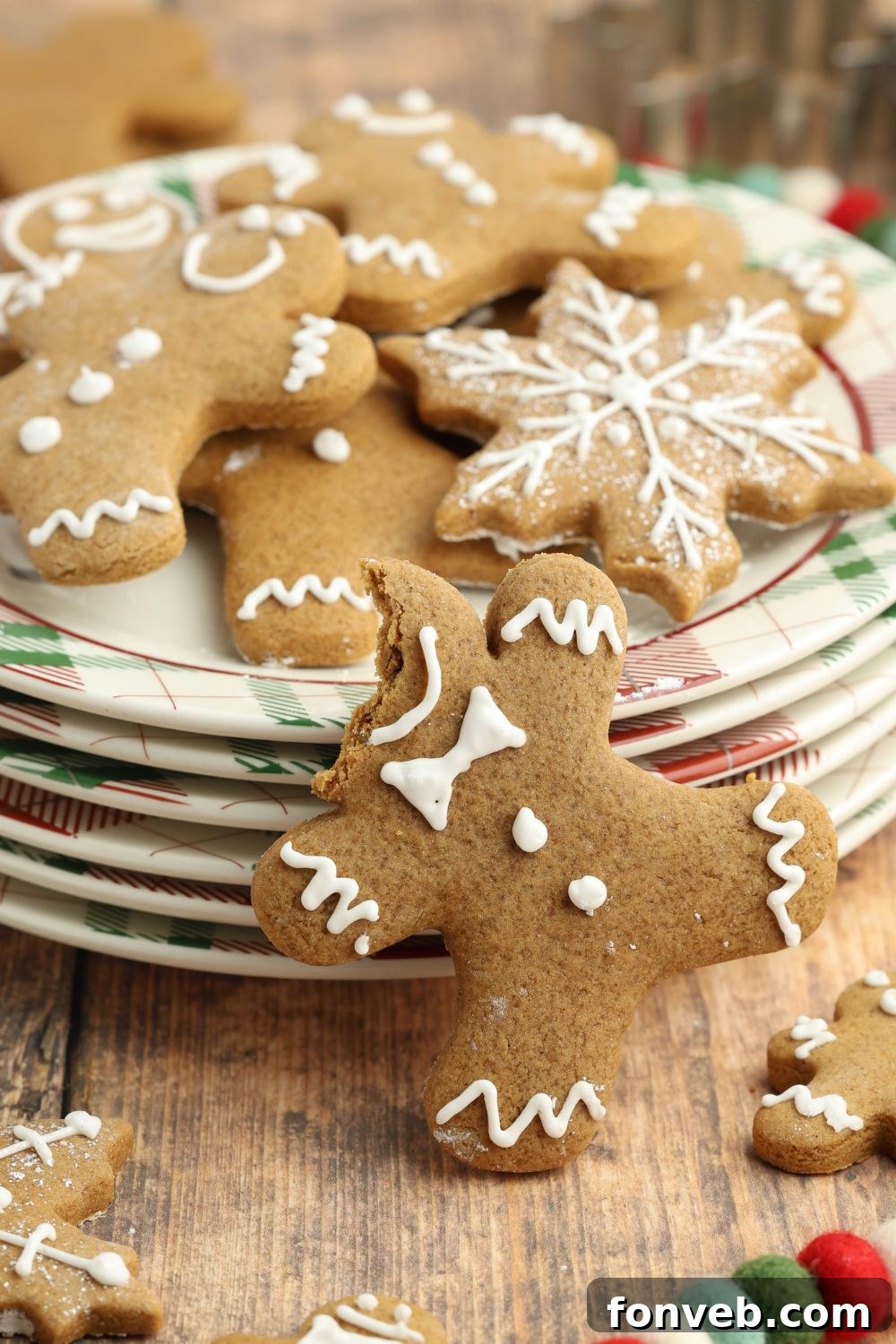Dazzling Christmas Gingerbread Adorned With Royal Icing 22 bite taken off head of gingerbread man on a stack of plates