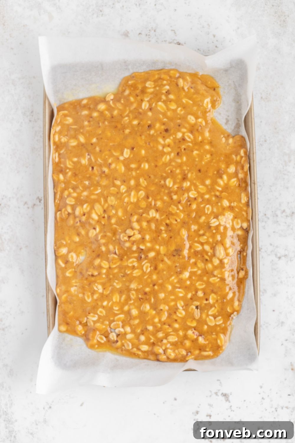 Classic Crunchy Peanut Brittle Made Simple 12 sheet pan with parchement paper with a spread out of Homemade Peanut Brittle