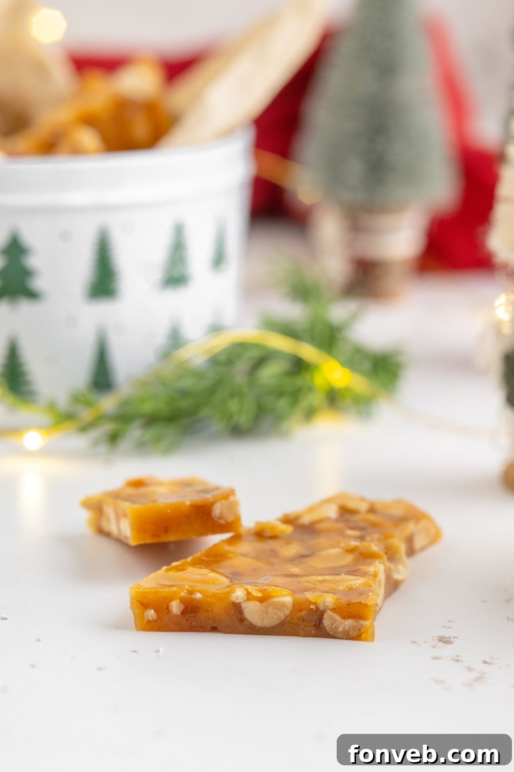 Classic Crunchy Peanut Brittle Made Simple 13 Homemade Peanut Brittle on a white table with Christmas decor behind it on table