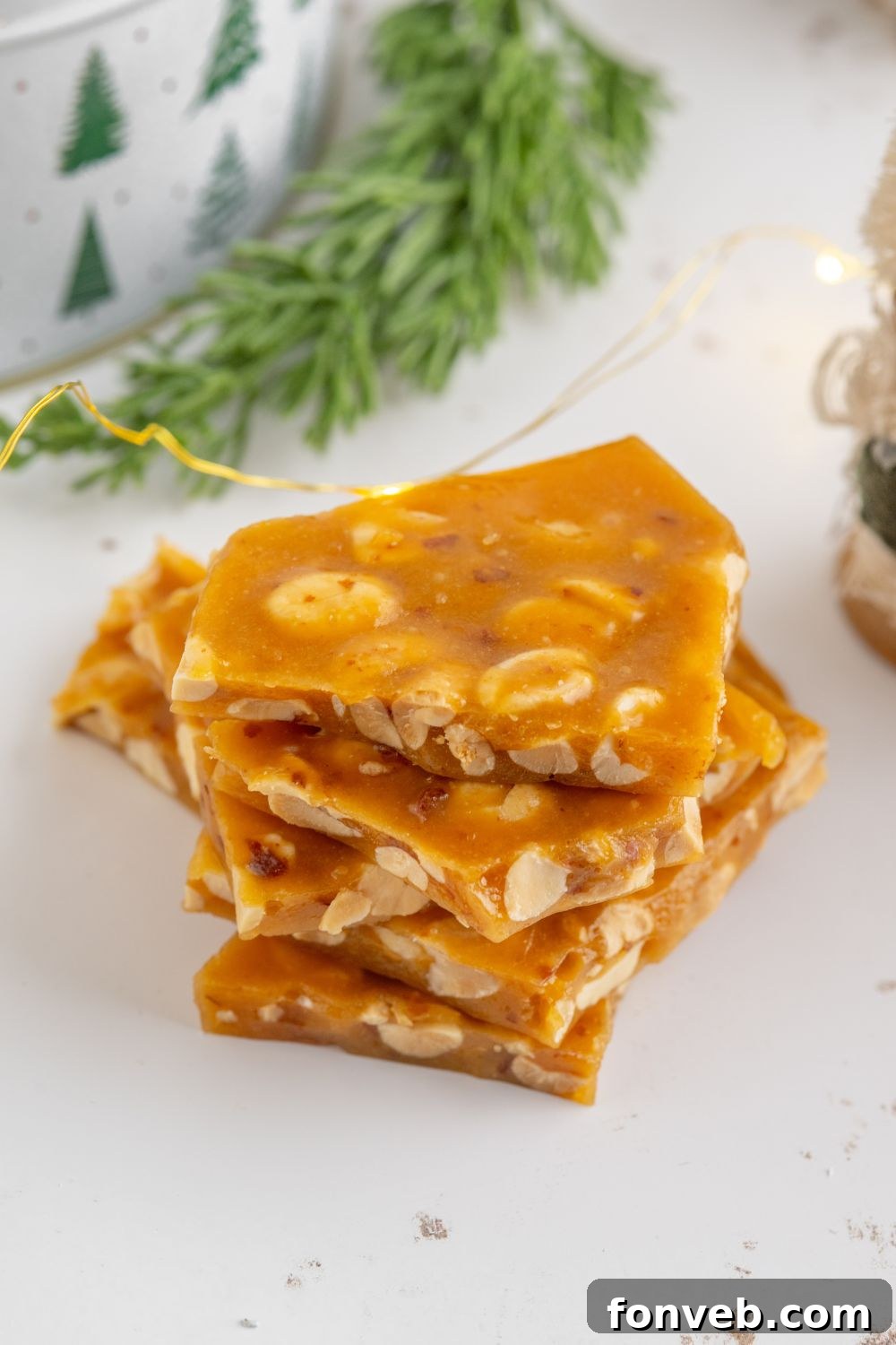 Classic Crunchy Peanut Brittle Made Simple 18 small batch peanut brittle broken into pieces on white table with Christmas decor behind table