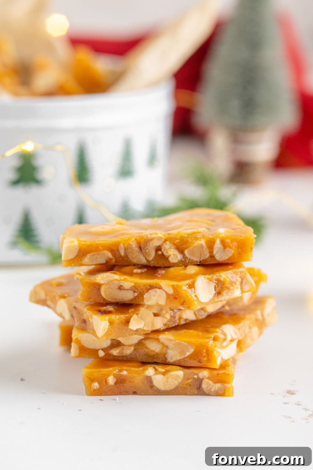 Classic Crunchy Peanut Brittle Made Simple 4 a stack of Homemade Peanut Brittle on table with a tin full of more behind it on table