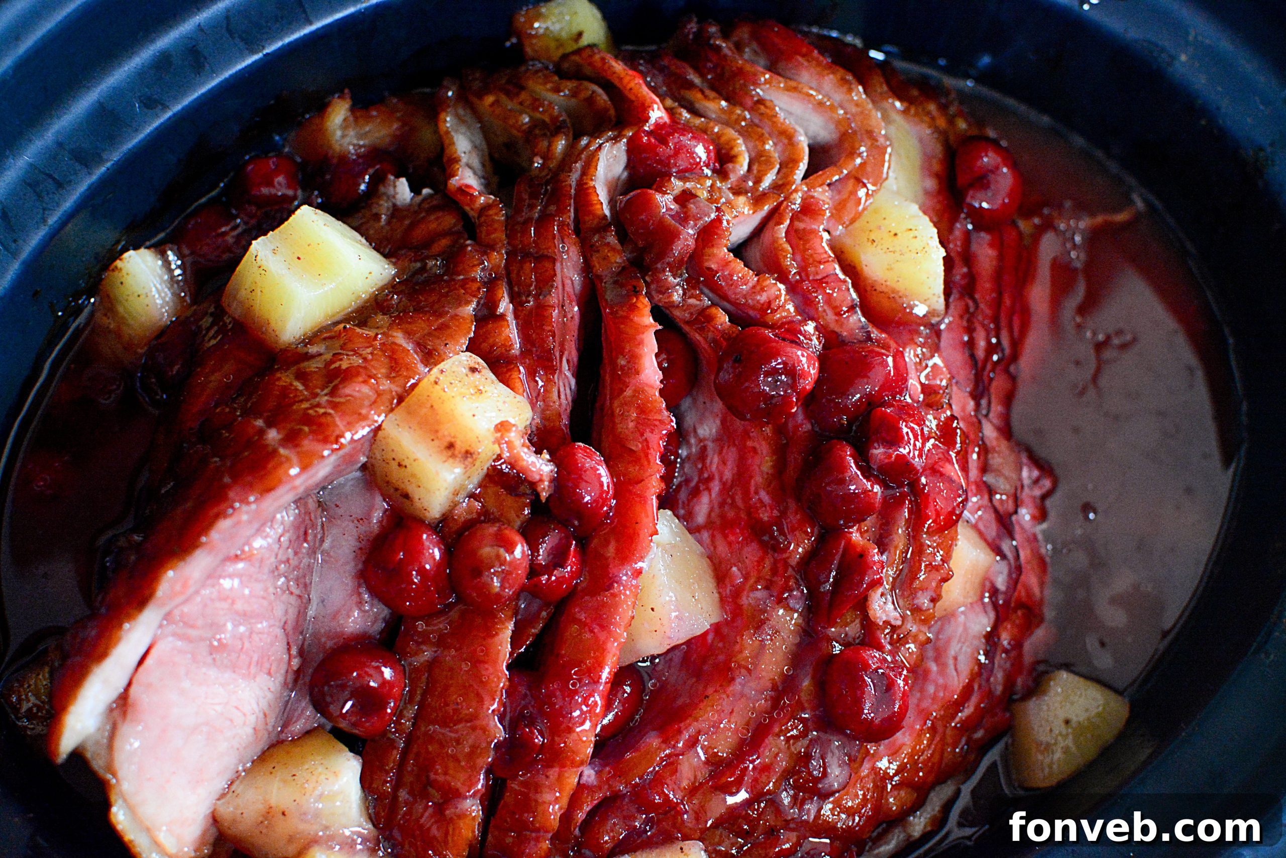 Slow Cooker Caramelized Pineapple Ham 8 Carved pineapple upside down ham on a serving plate with decorative elements.
