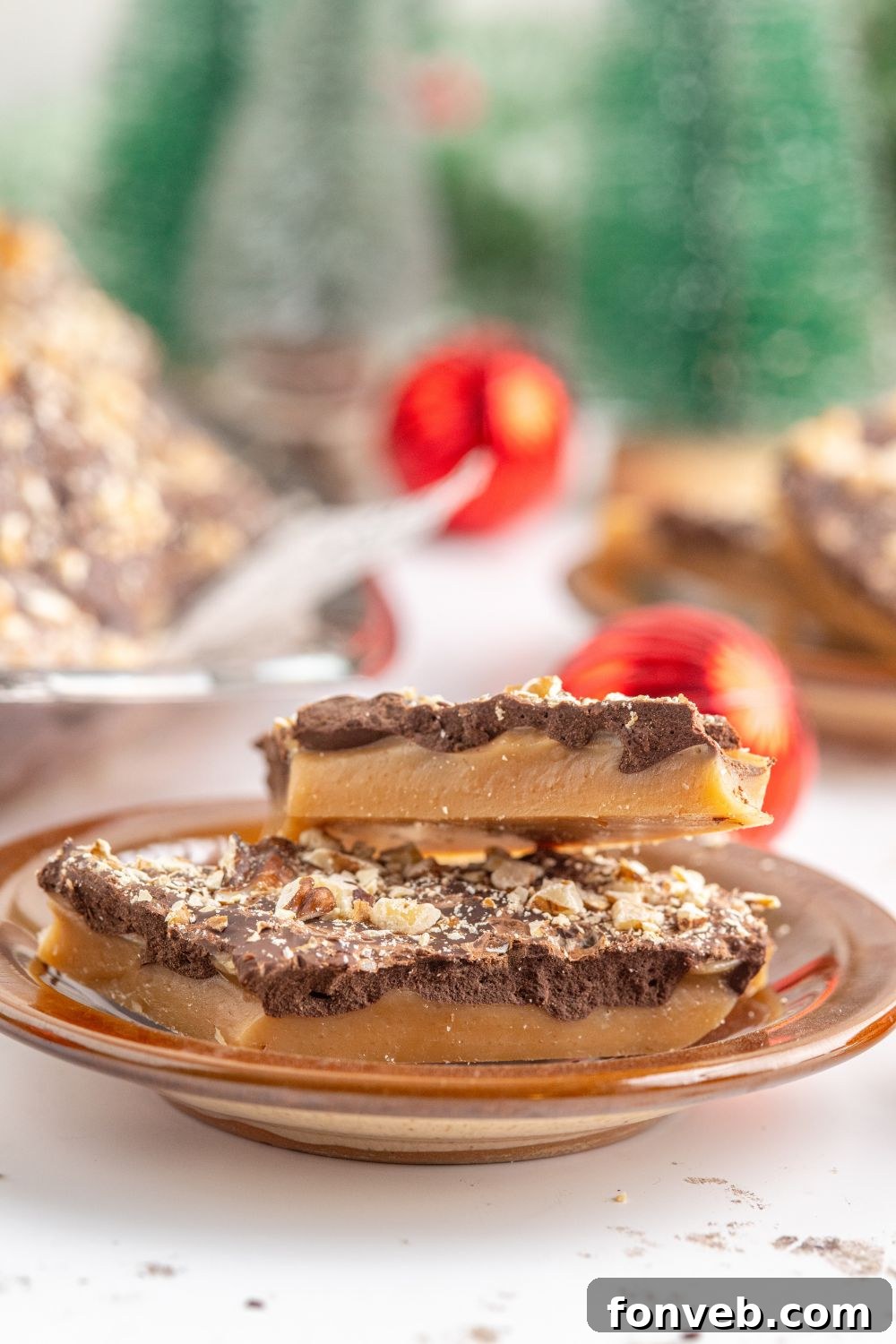 English Toffee on a plate with more behind it and some red ornaments on table 