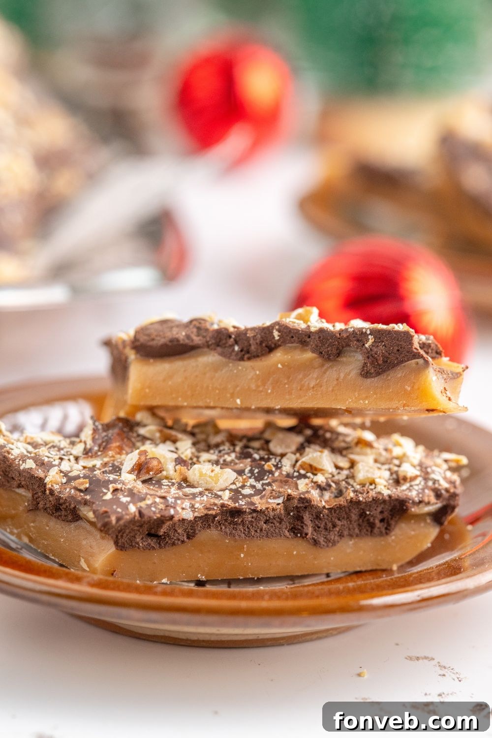 English Toffee on a plate with red ornaments behind it on table 