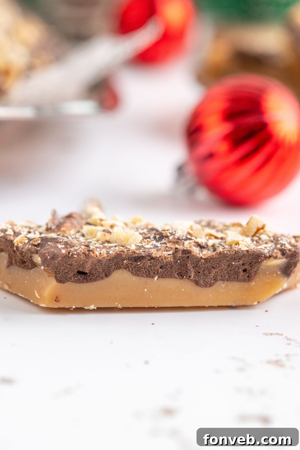 a piece of English Toffee on a white table with a Christmas ornament behind it 