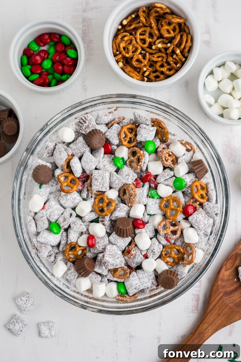 glass bowl on white table with fresh Christmas Chex Mix in it 