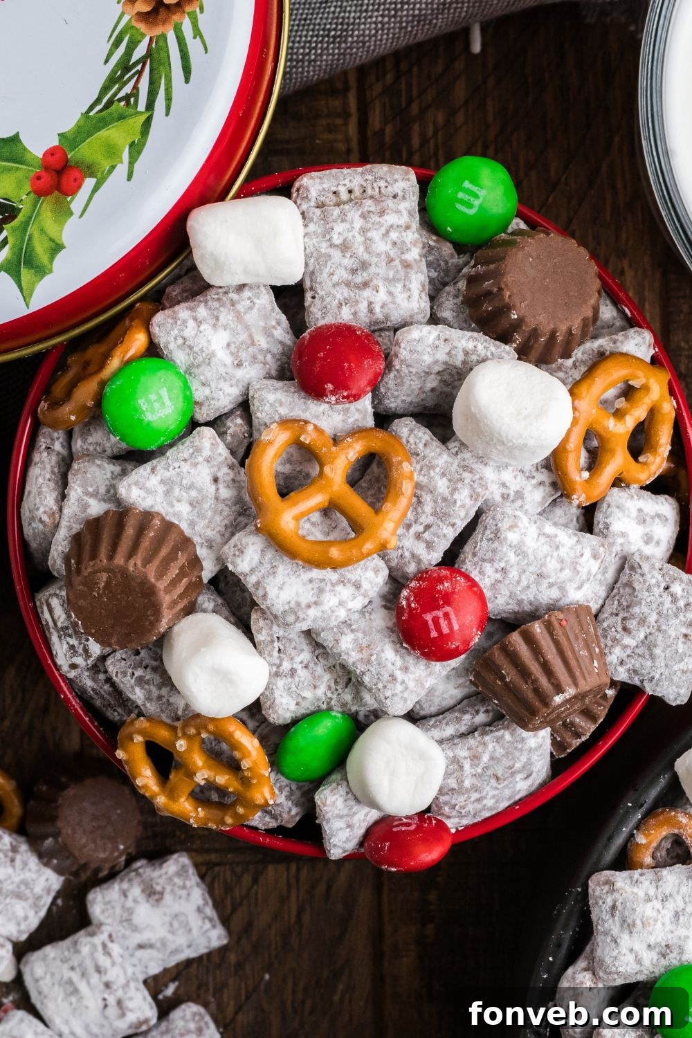 powdered sugar Chex mix in a metal gift tin with lid to side and more of the snack mix placed around the table