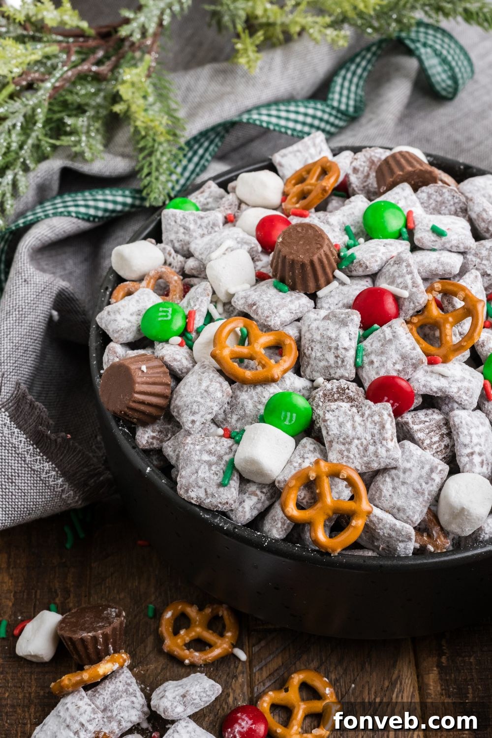 side view of a bowl with Christmas Chex Mix and more puppy chow and toppings falling out of bowl 