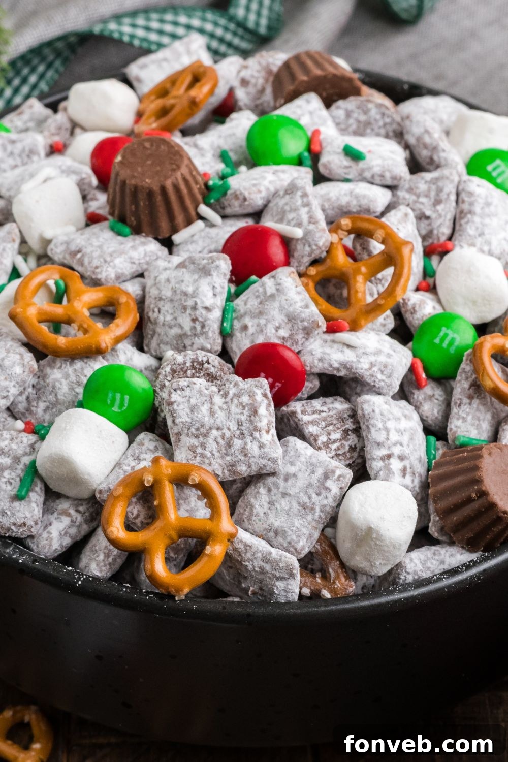 close up view of Christmas Chex Mix in a black bowl on table 