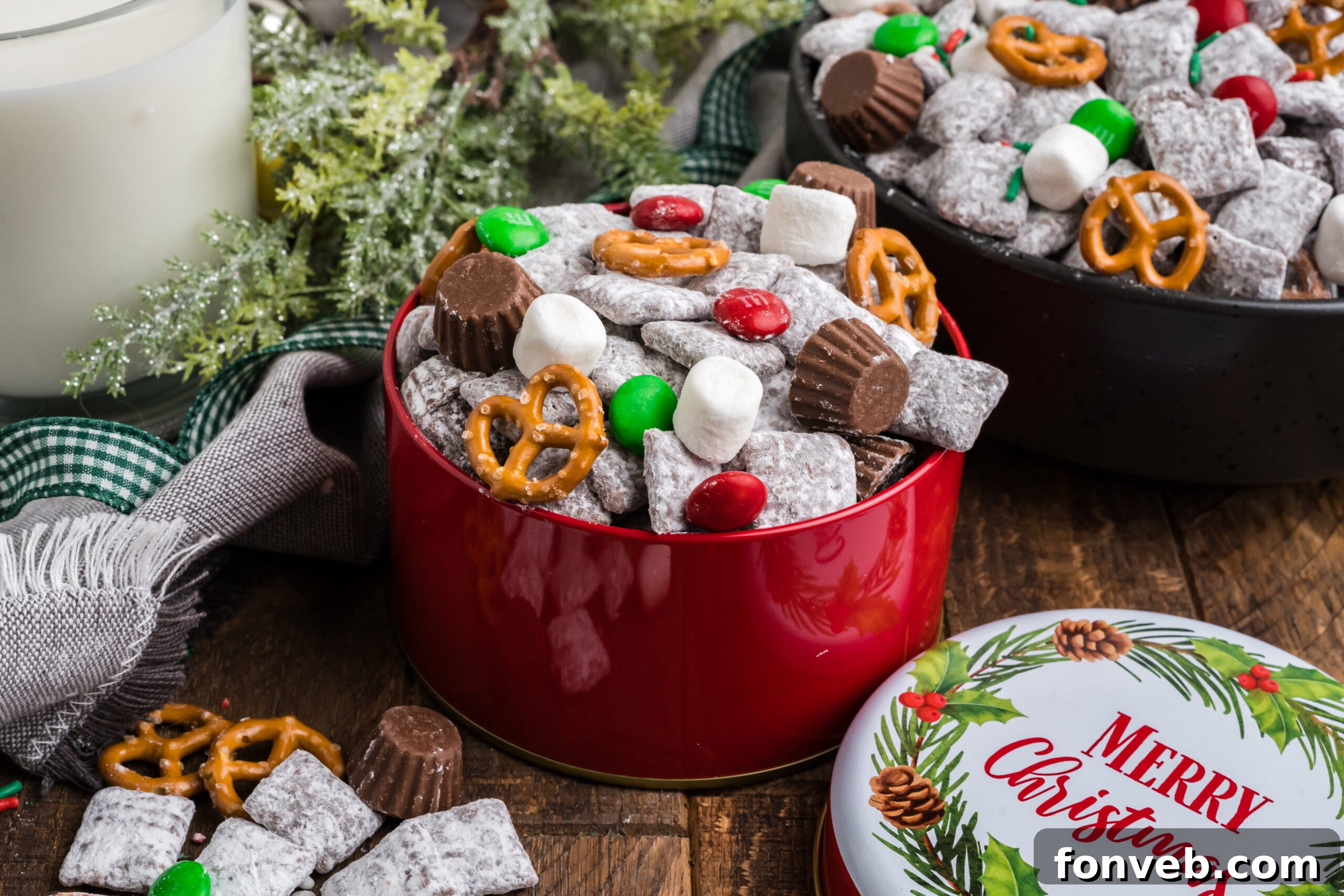 Christmas tin with Christmas Chex Mix and more puppy chow and toppings falling out of bowl 