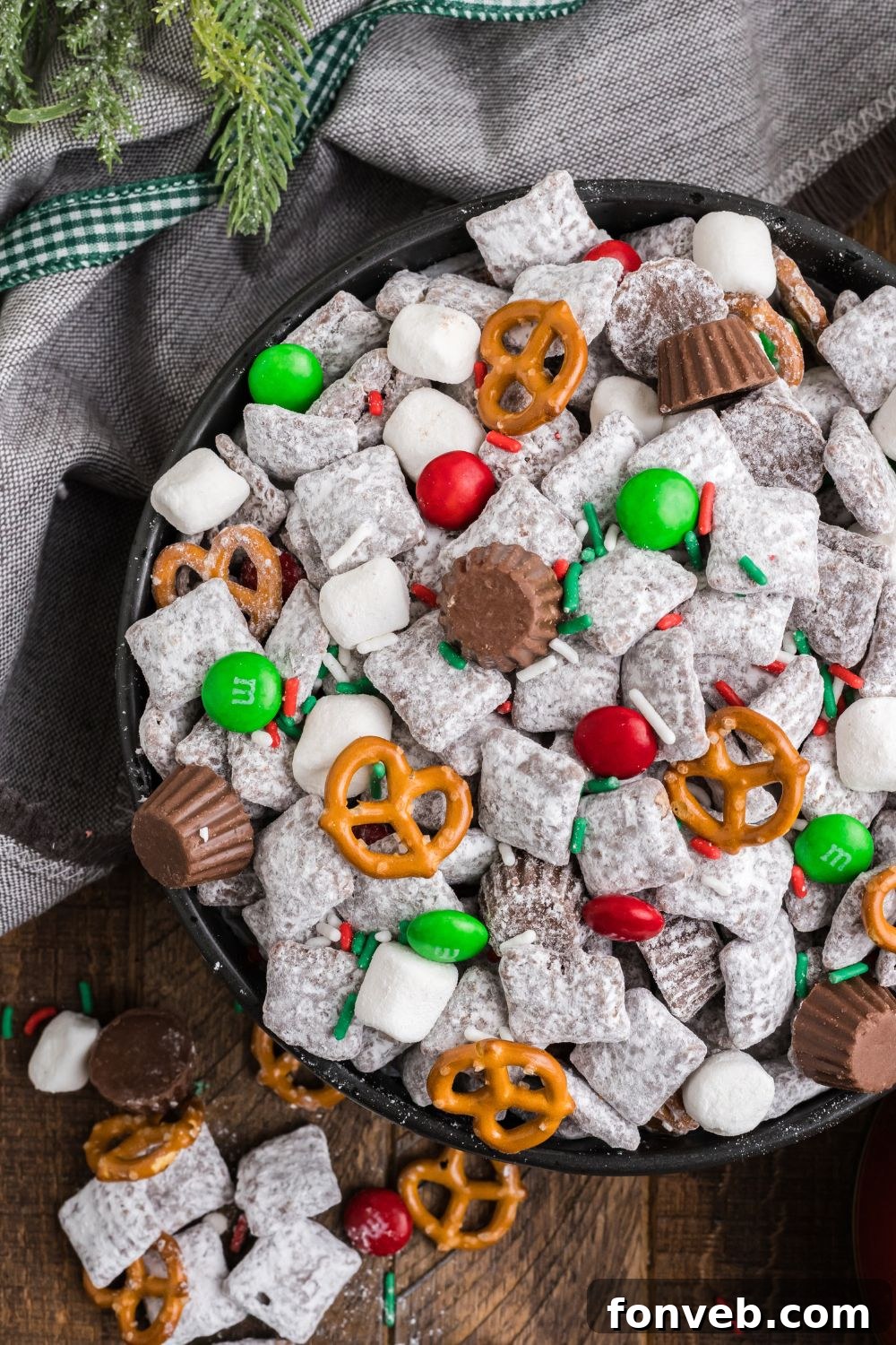 looking down on wooden table with Christmas Chex Mix in it that is loaded with crispy puppy chow 