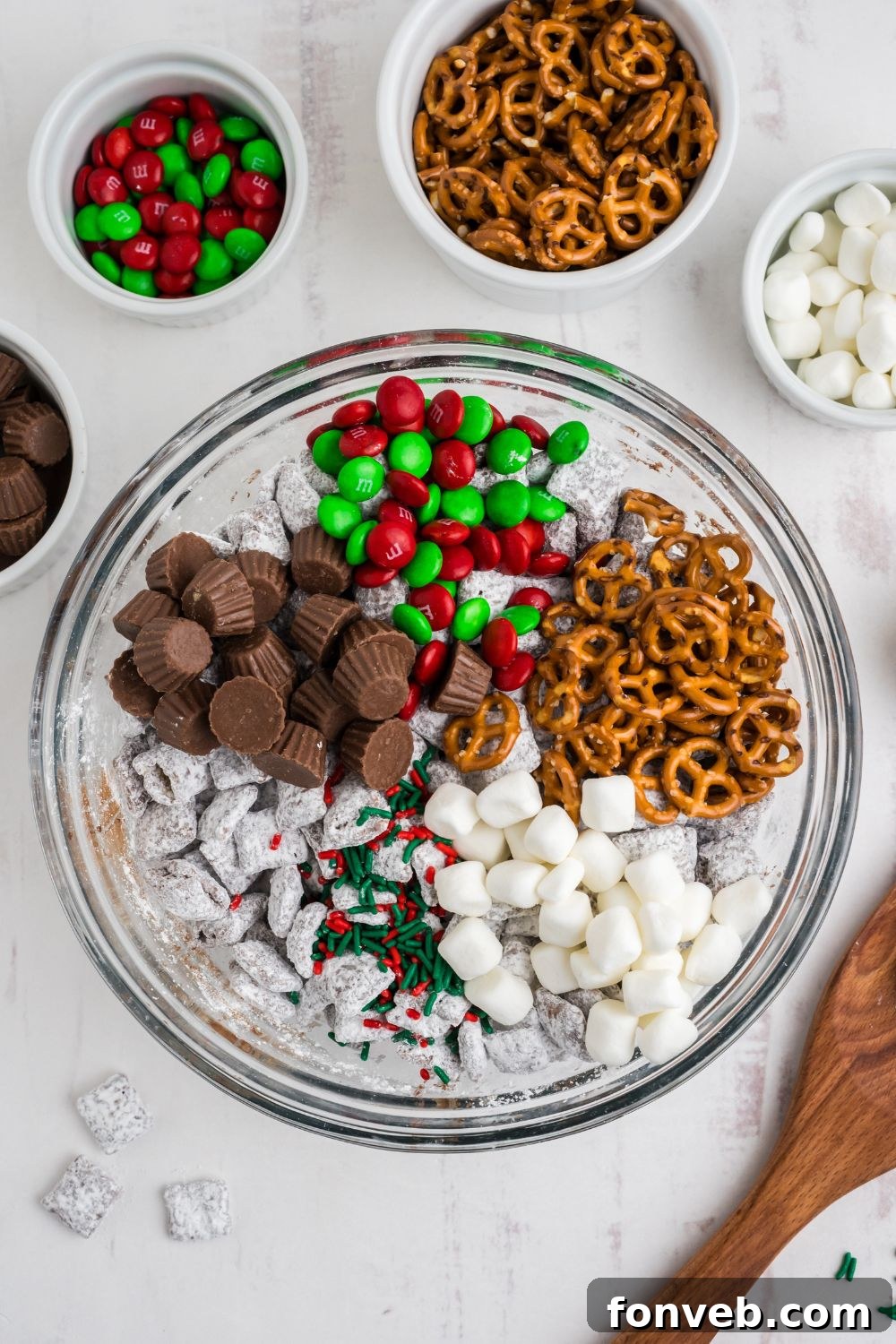 all the mix in ingredients for Christmas Chex Mix sitting on top of a bowl of puppy chow 