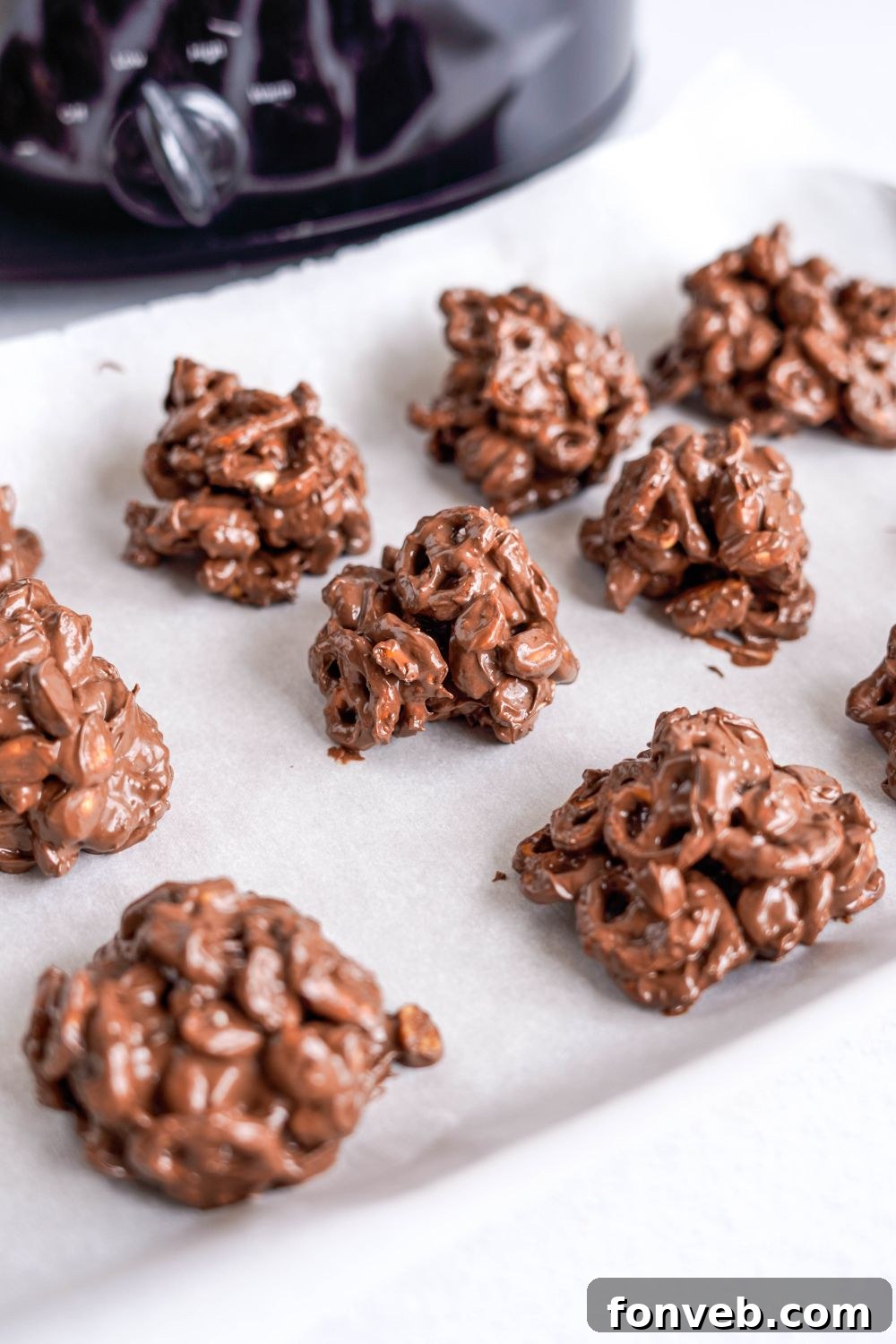 Sweet and Salty Slow Cooker Holiday Clusters 13 scoops of Crockpot Chocolate Pretzel Christmas Candy on parchment paper