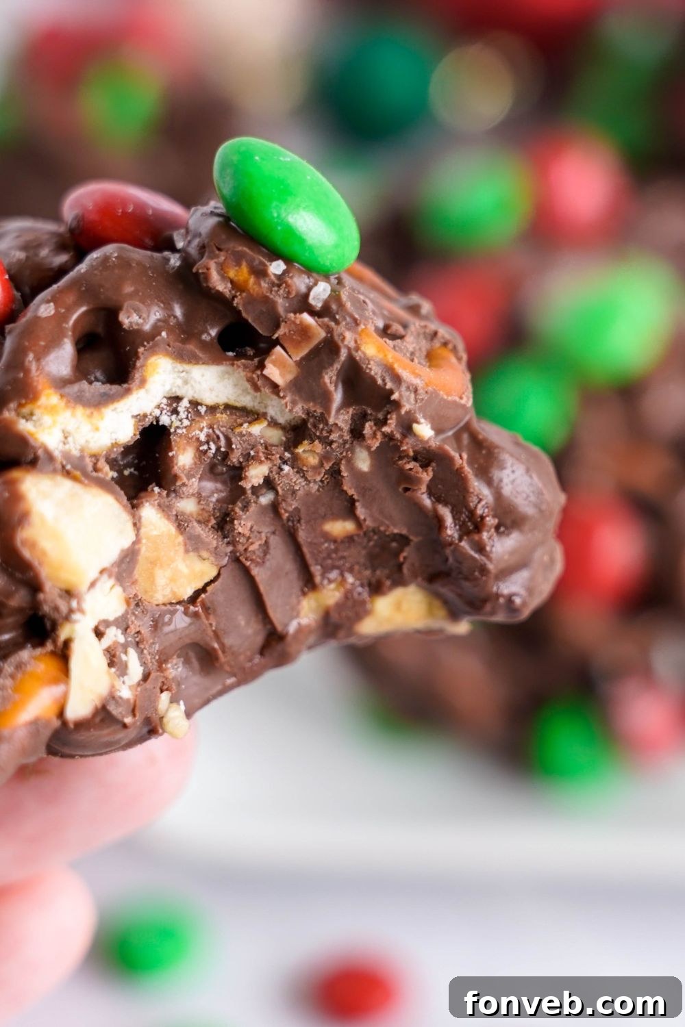 Sweet and Salty Slow Cooker Holiday Clusters 17 Crockpot Chocolate Pretzel Christmas Candy with a bite taken out of it