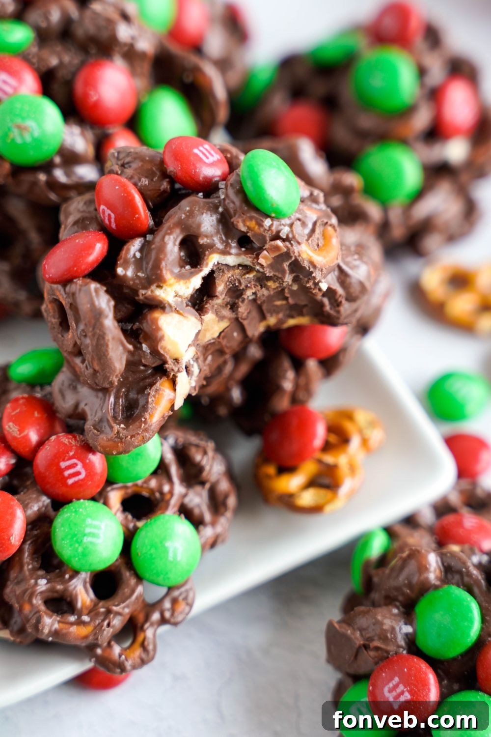 Sweet and Salty Slow Cooker Holiday Clusters 18 Crockpot Chocolate Pretzel Christmas Candy on a white platter with a bite taken out of it