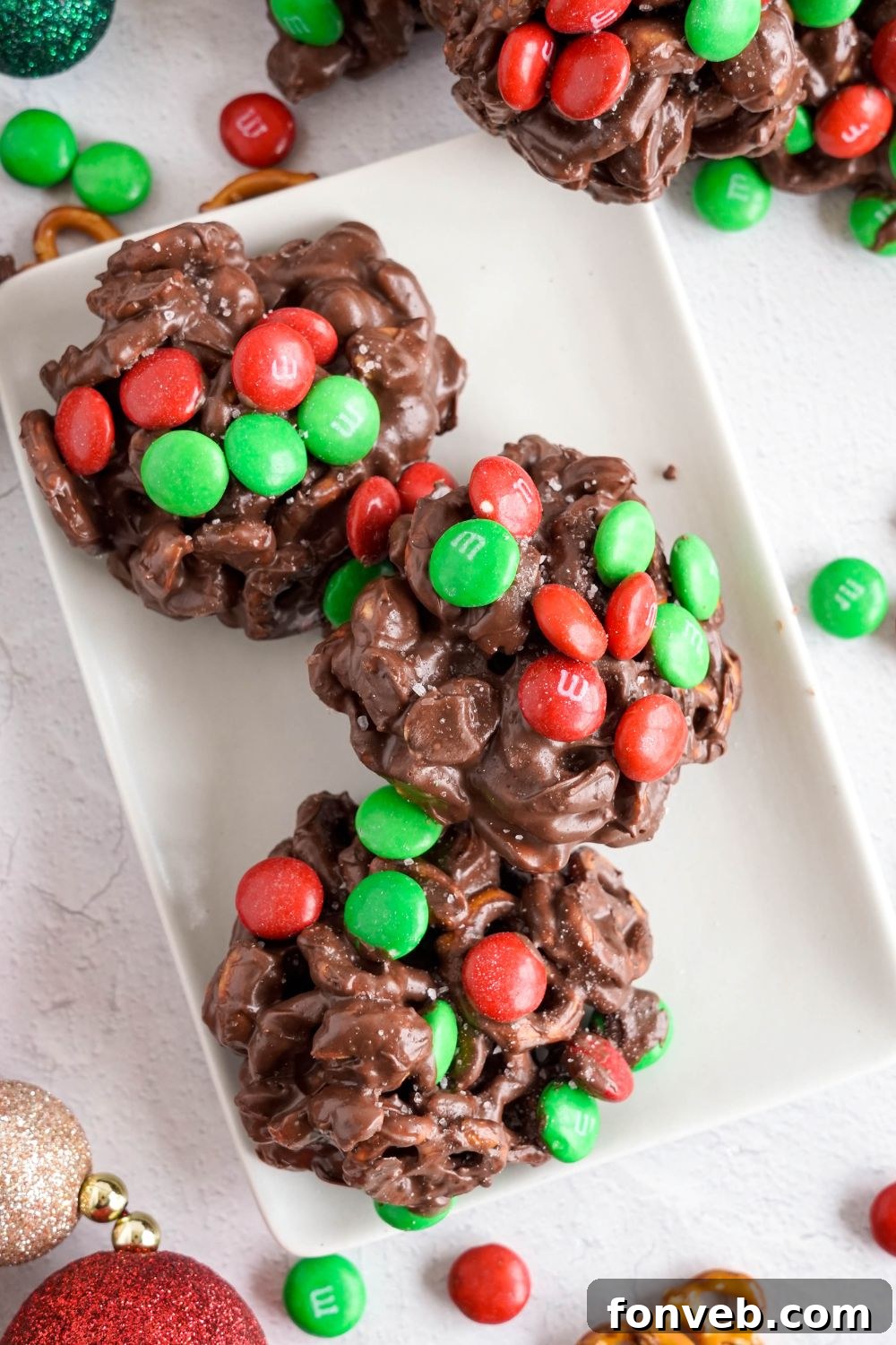 Sweet and Salty Slow Cooker Holiday Clusters 21 Crockpot Chocolate Pretzel Christmas Candy in a row on a white rectangle tray