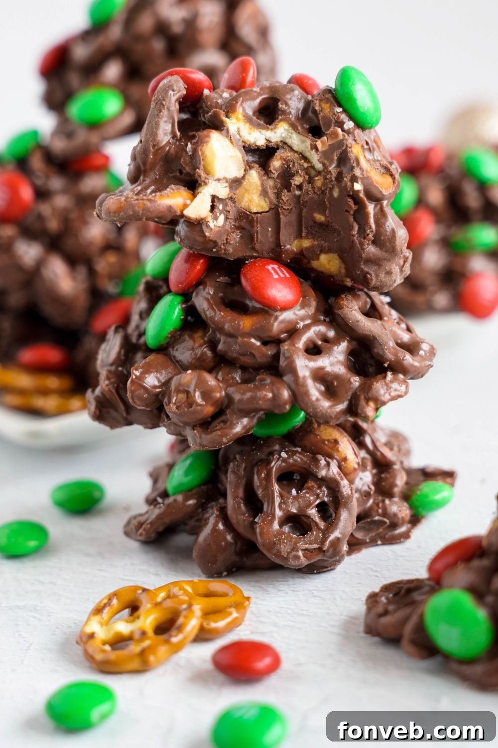 Sweet and Salty Slow Cooker Holiday Clusters 23 Crockpot Chocolate Pretzel Christmas Candy spread around table with some candies stacking up