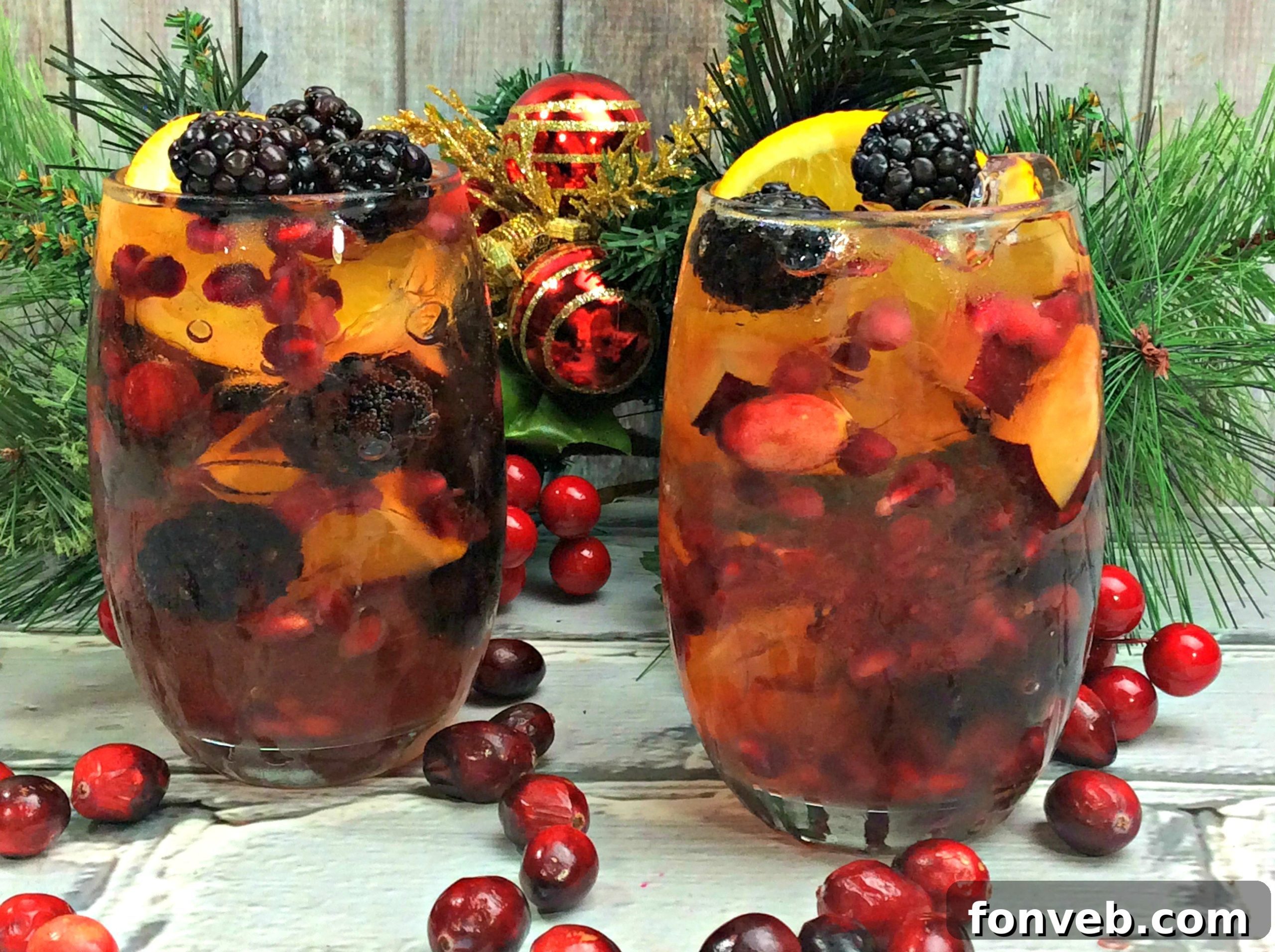 Close-up of a glass of white wine sangria garnished with blackberries, cranberries, and an orange slice, on a bright, inviting background.