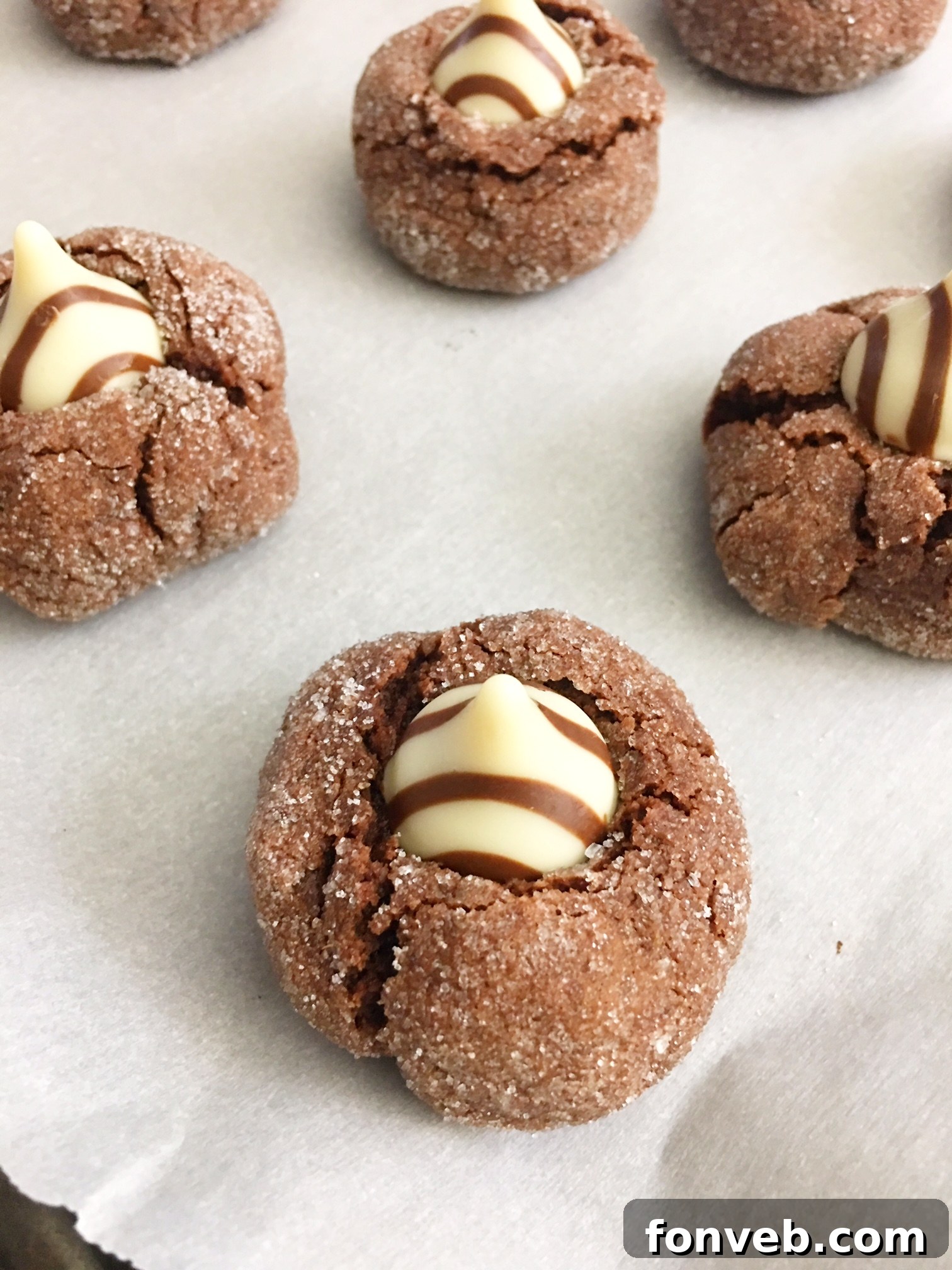 A generous pile of freshly baked Hershey's Hugs Blossom Cookies, showcasing their appealing golden-brown edges and soft centers topped with iconic chocolate kisses, ready to be enjoyed.