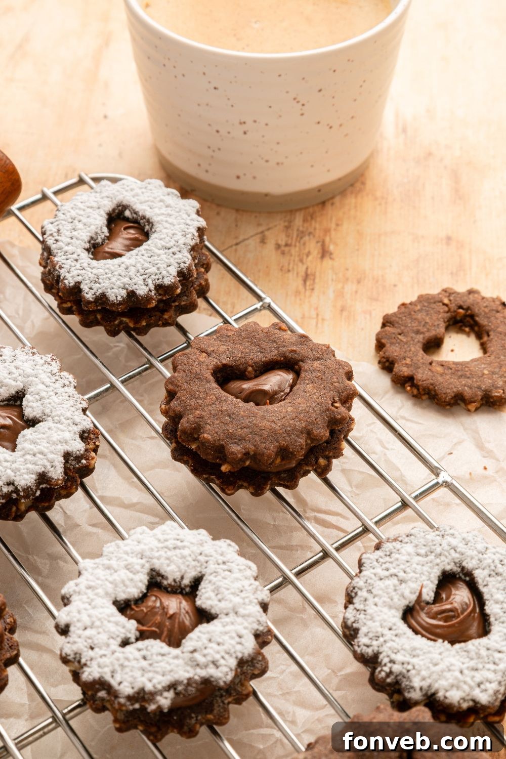 Chocolate Linzer Cookies on a cooling rack with a cup of milk to the side of the table 