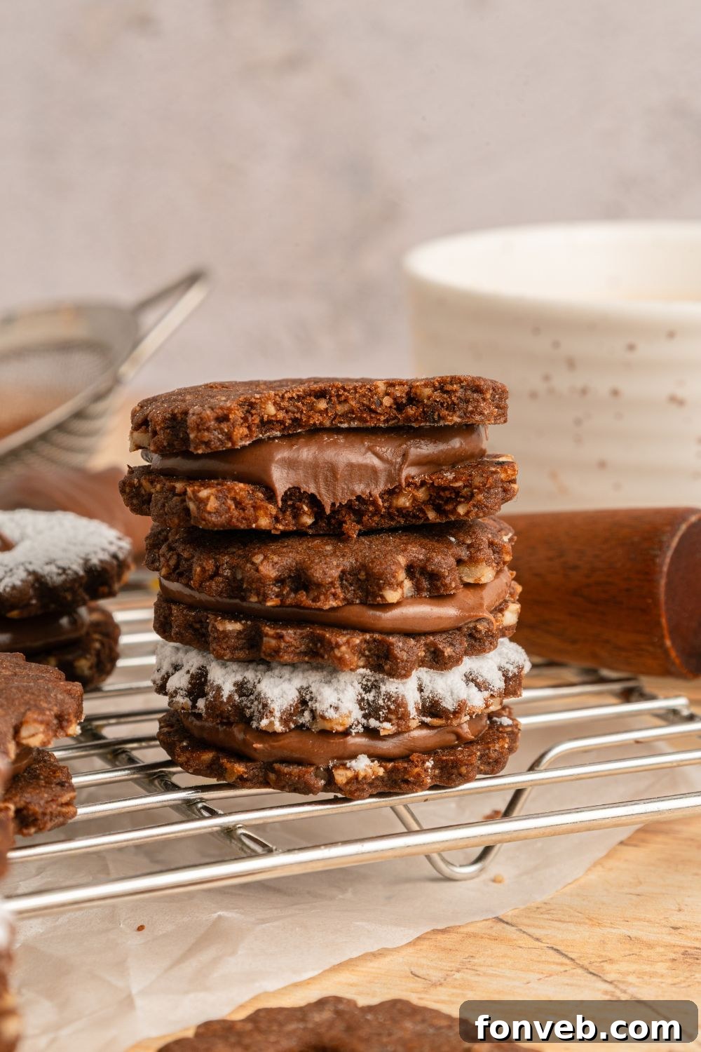 Chocolate Linzer Cookies stacked on the tray with one of the cookies with a bite taken out of it 