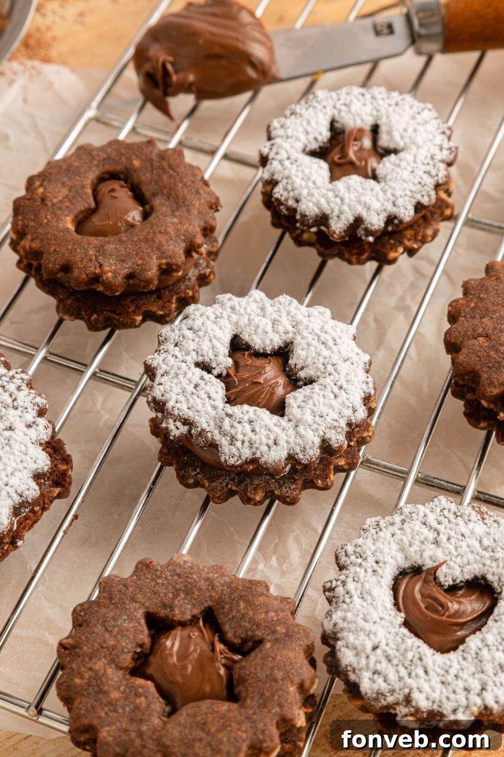 Chocolate Linzer Cookies spread out on table wit ha few of the cookies dusted with powdered sugar 