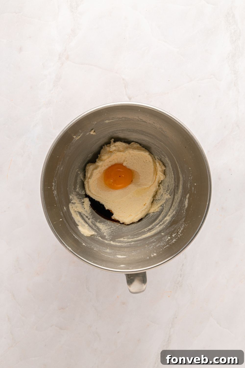 creamed butter with egg in a metal mixing bowl 