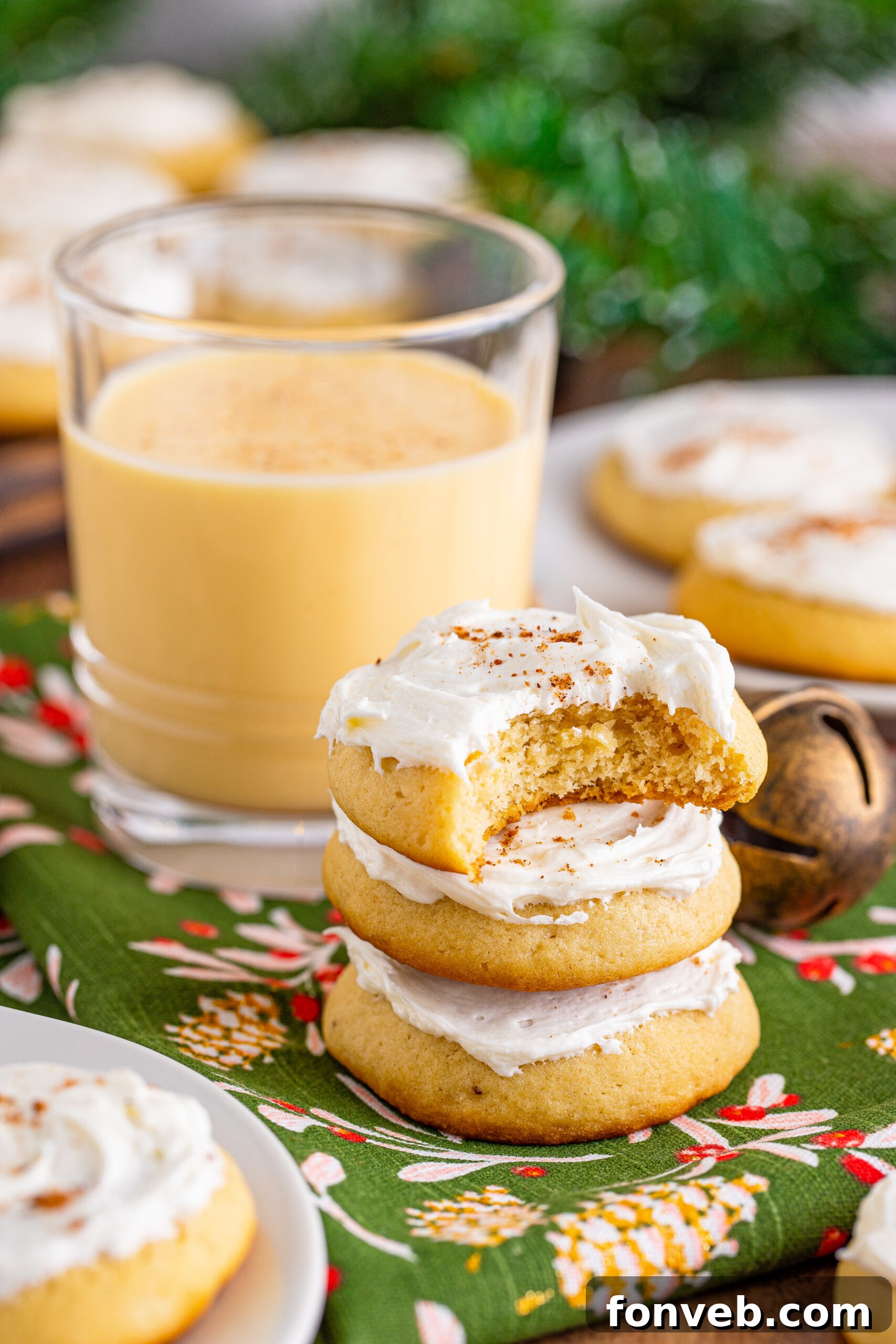 Soft Frosted Eggnog Cookies stacked on a table with a bite missing from the top cookie
