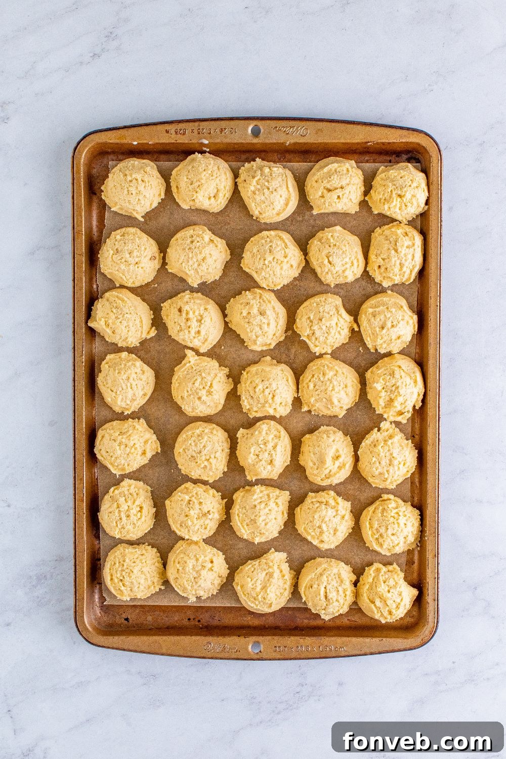 raw eggnog cookie dough balls on a baking sheet on table
