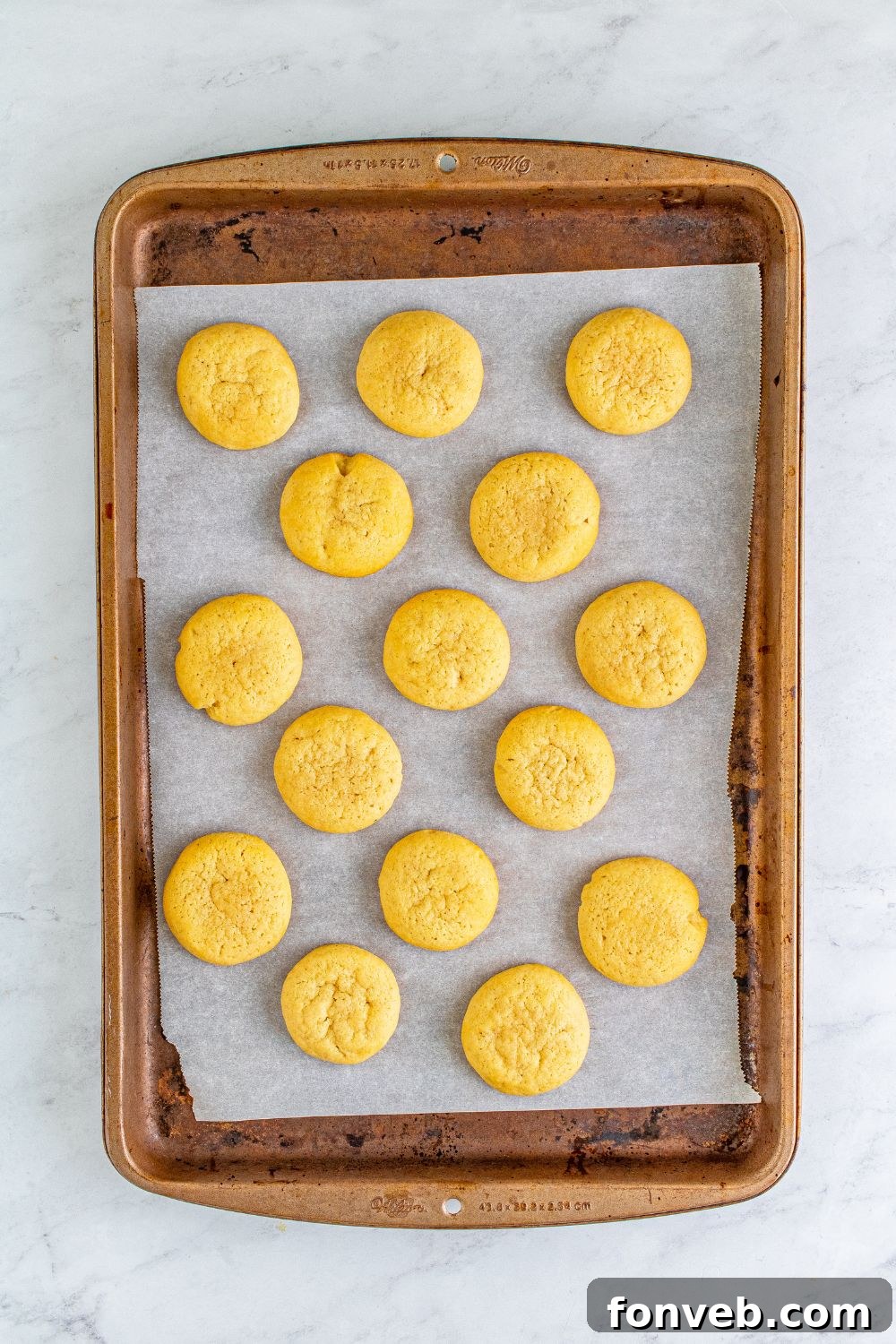 baked cookies on a cookie sheet on table with parchment paper