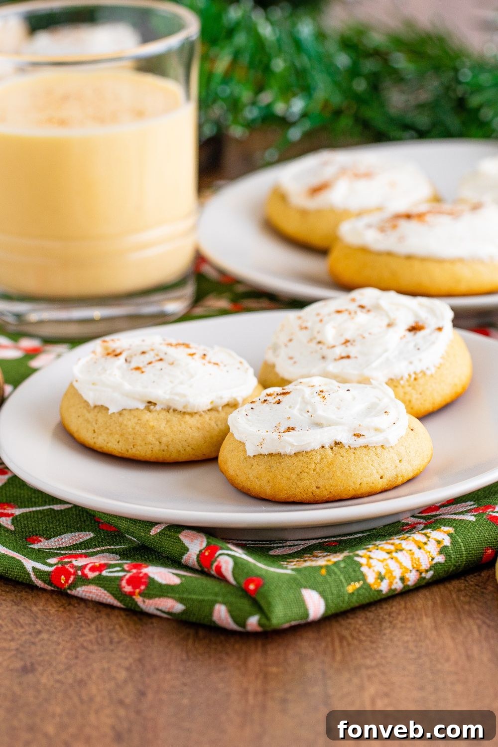 plates full of cookies with eggnog to side in a clear glass and a green towel under the plate