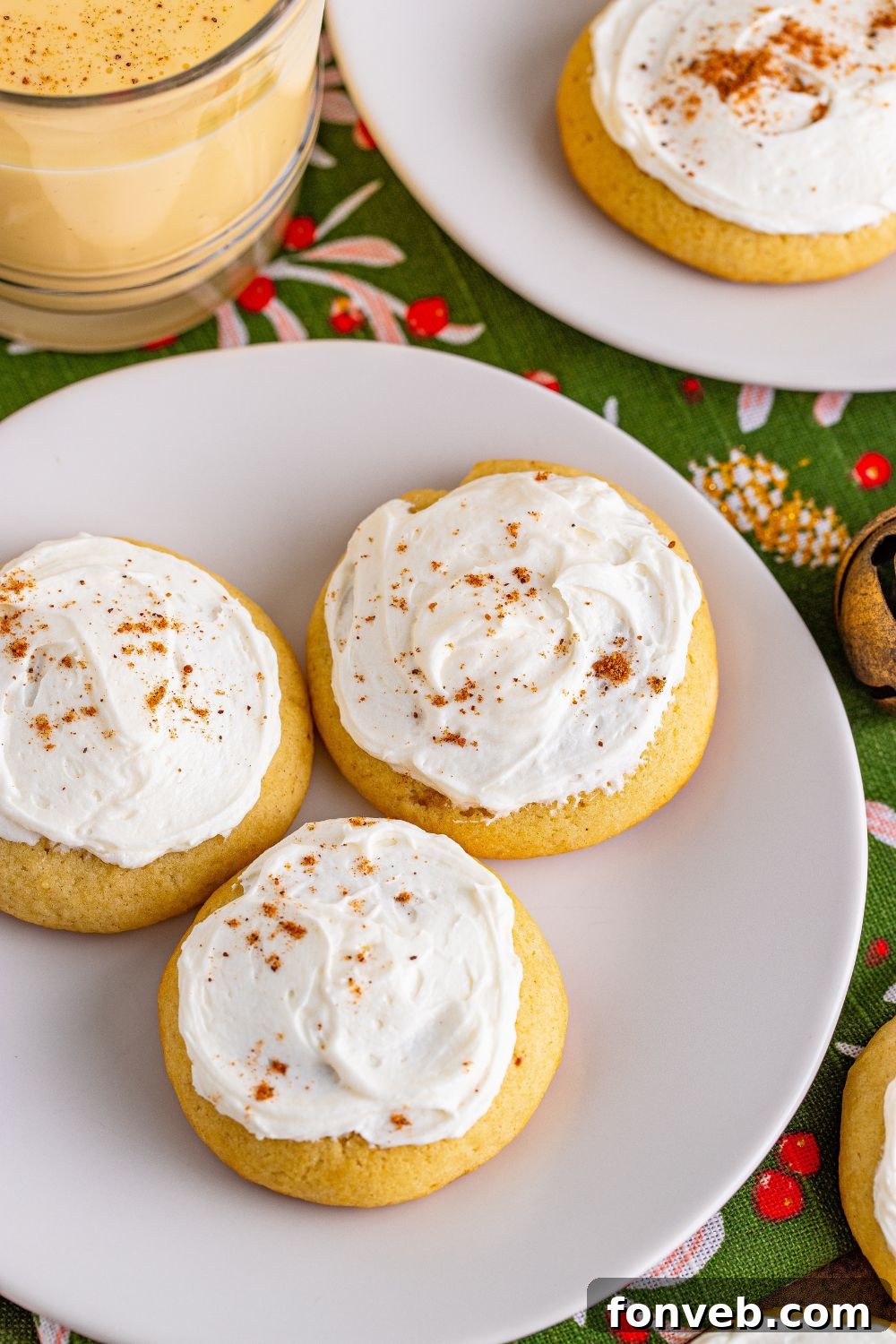 Soft Frosted Eggnog Cookies on white plates on the table with eggnog on the side