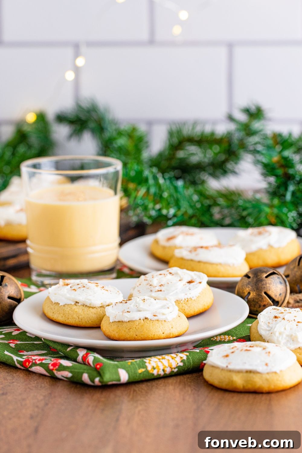 Christmas themed table with plates of eggnog cookies and a glass of eggnog to side