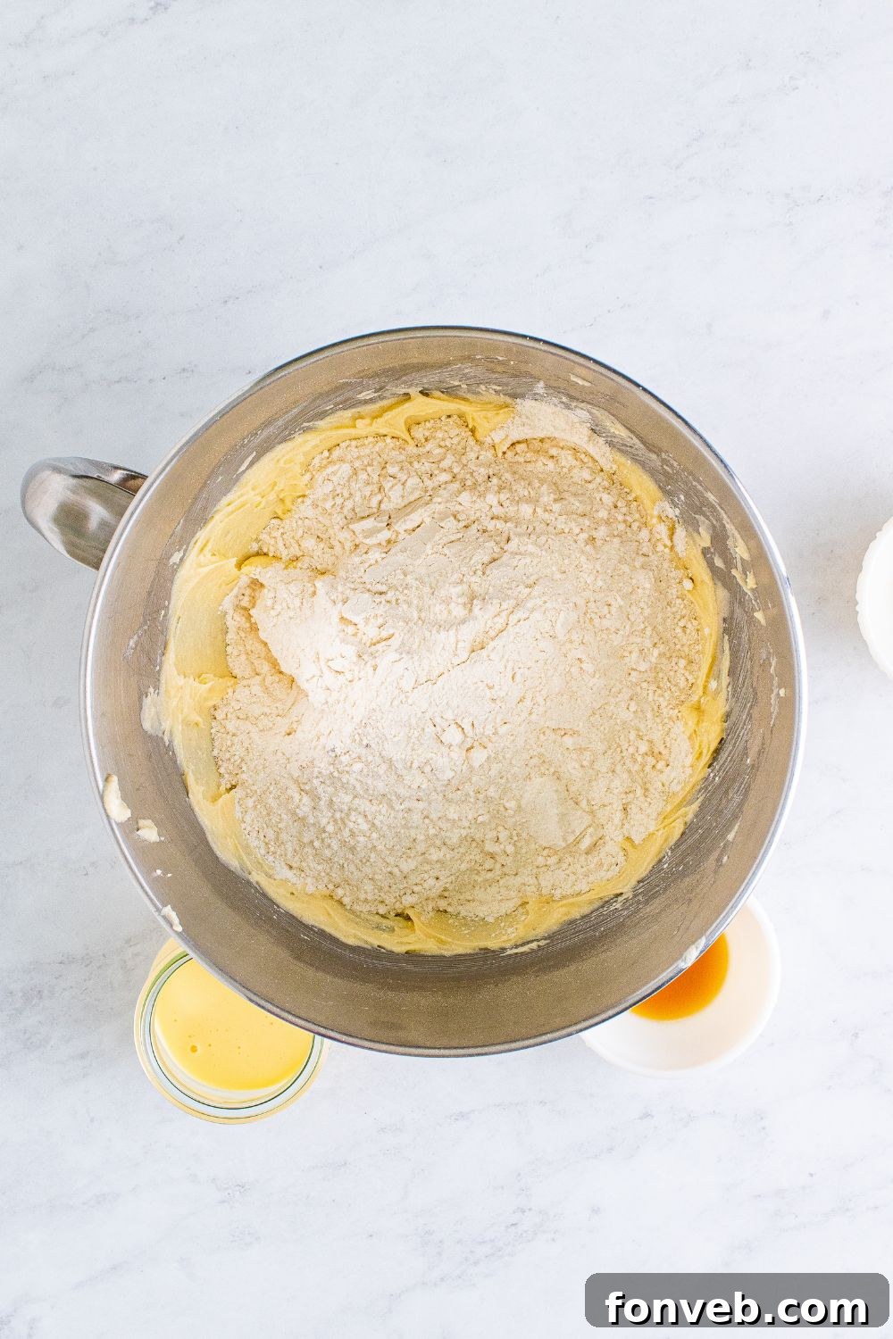 a metal mixing bowl full of creamed butter mixture and dry ingredients
