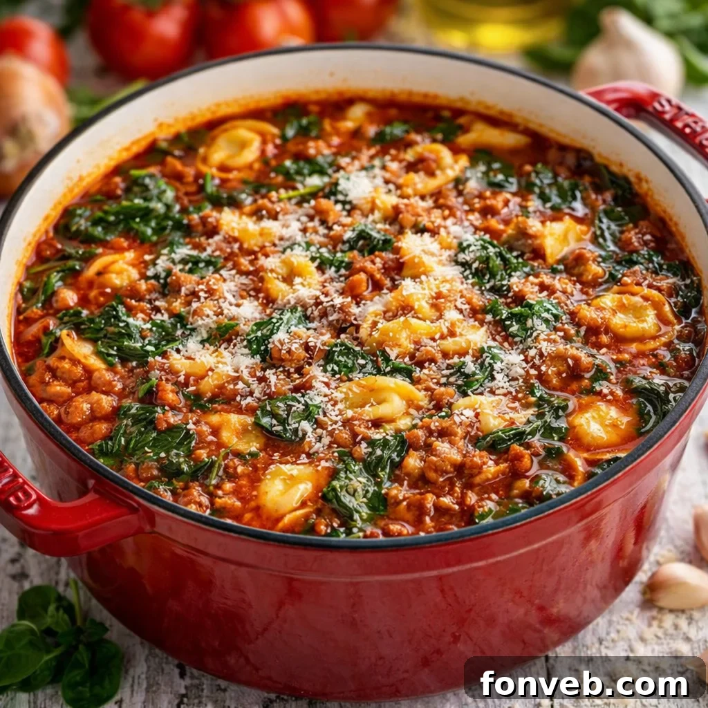 Hearty One-Pot Sausage Spinach Tortellini Soup in a vibrant red Dutch oven, ready to be served