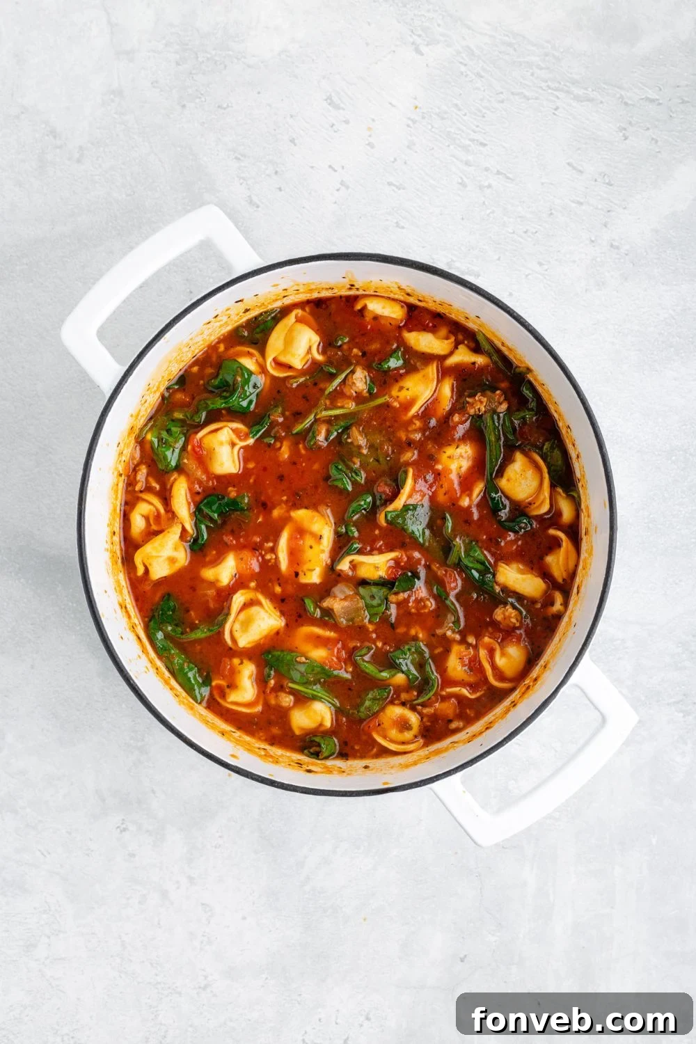 A perfectly cooked pot of Sausage Tortellini Soup, rich and inviting, resting on a white counter after preparation